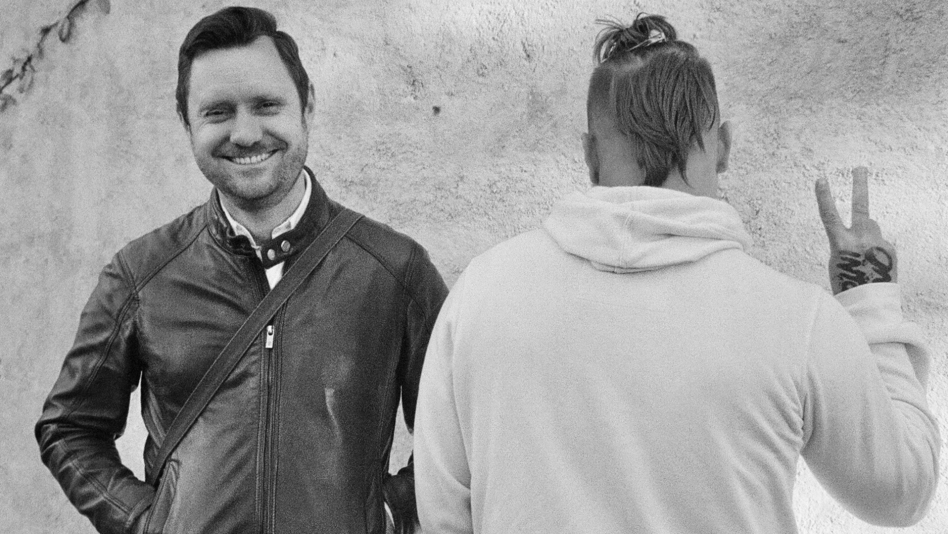 Black-and-white photo of Terri & Sandy employees Mike and Todd smiling together, with Mike posing with a peace sign.