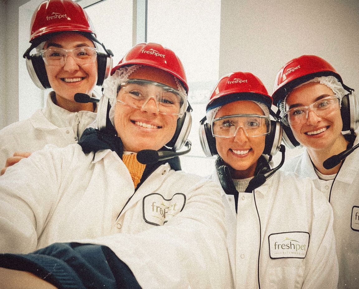 Freshpet team members wearing branded safety gear during a facility tour.
