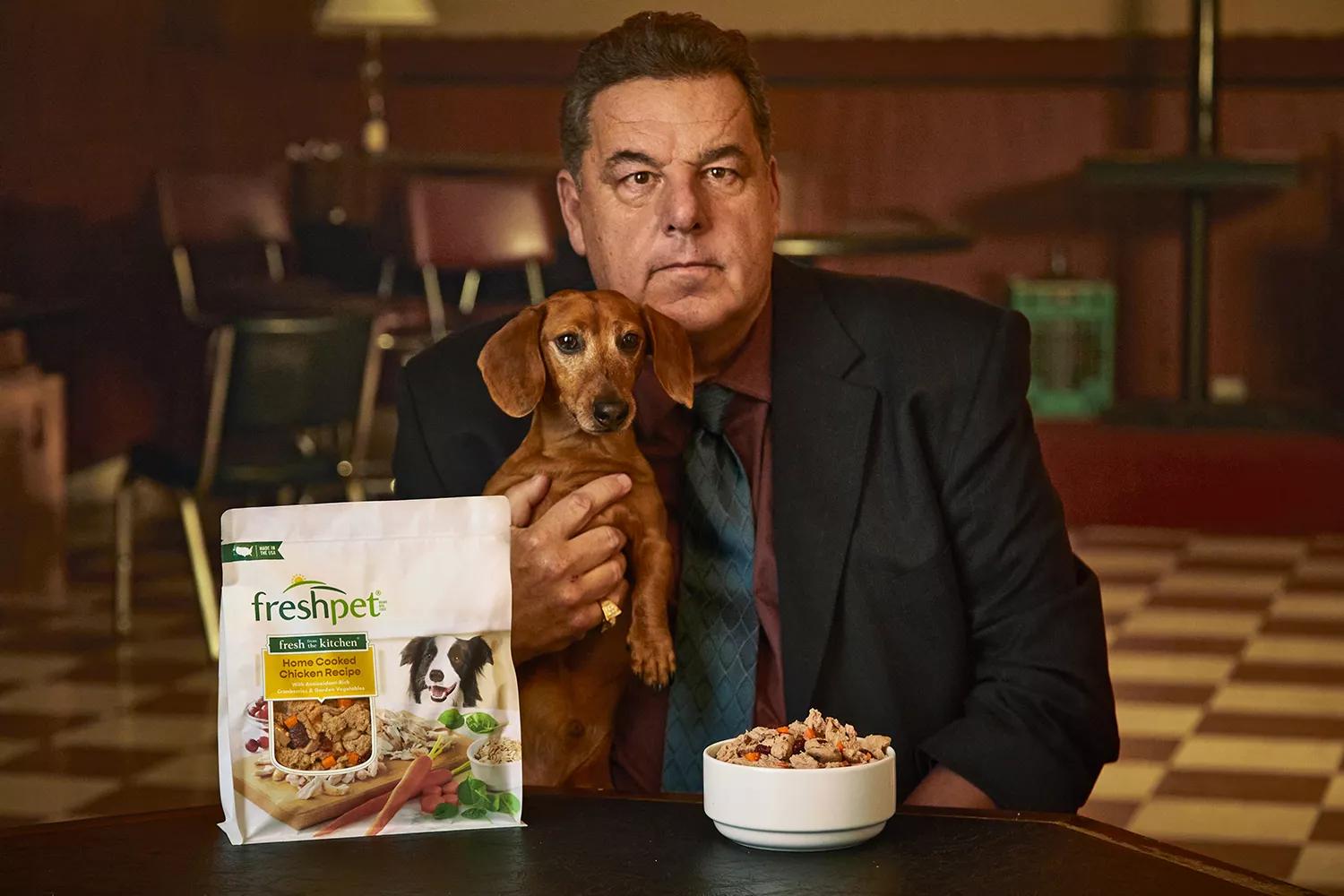 Steve Schirripa holds a dachshund beside Freshpet Fresh from the Kitchen dog food and a bowl of fresh dog food.