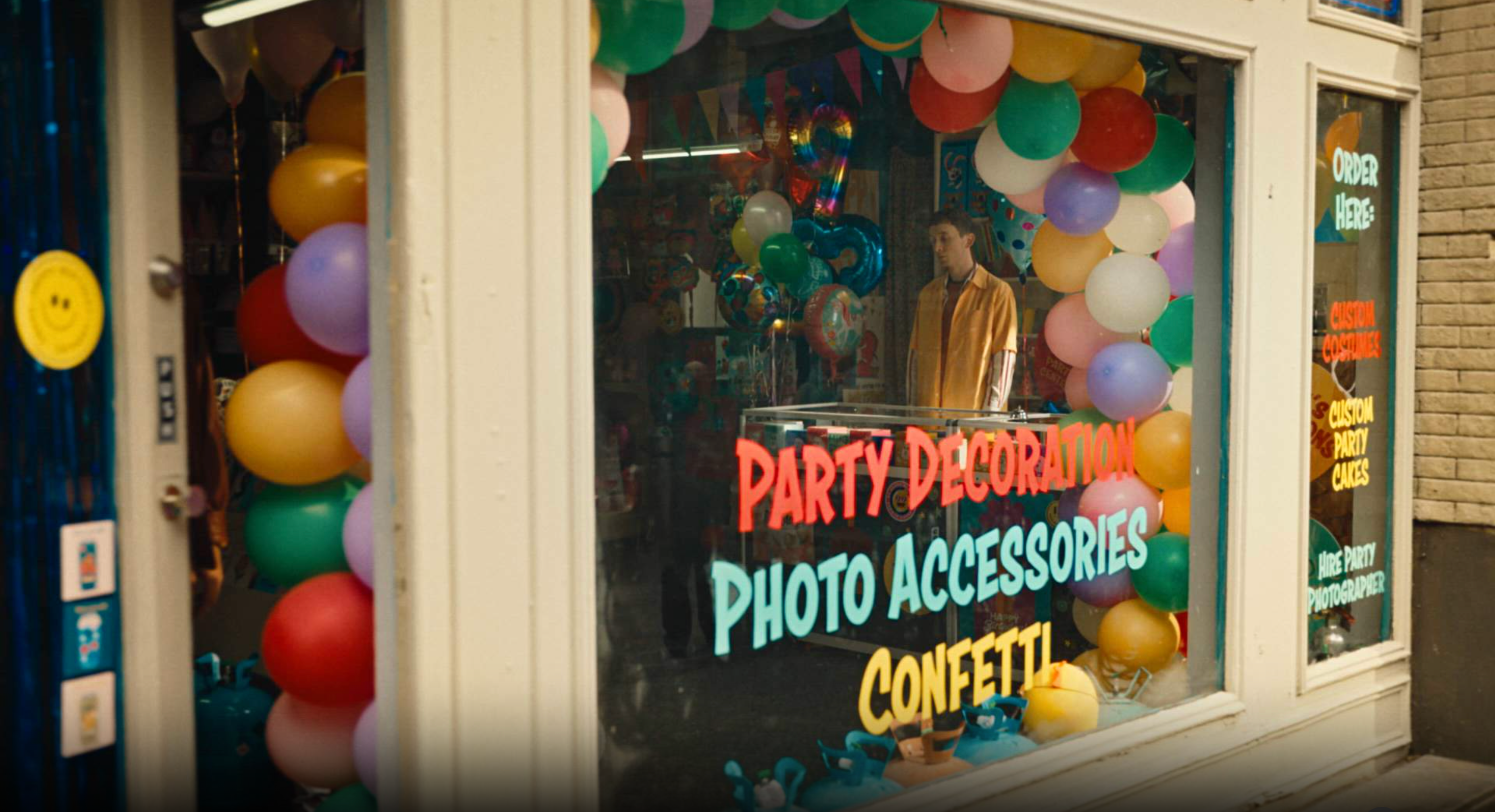 Colorful balloon display in a party supply storefront with a person standing inside