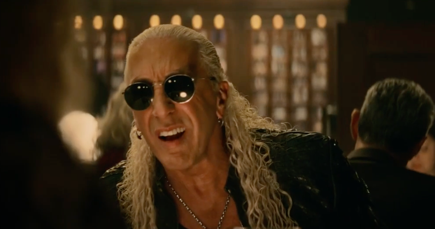 Man with long blond hair and sunglasses in a scene from an entertainment advertising campaign.
