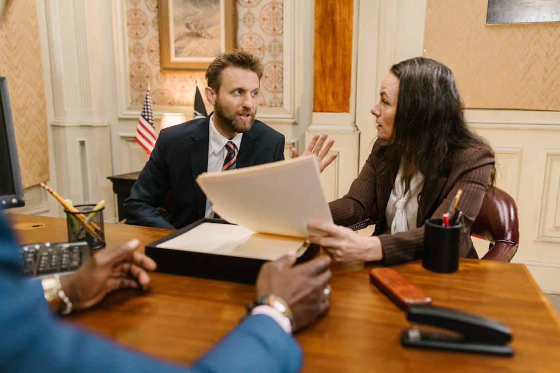 A lawyer and client in formal discussion across a desk in a professional office setting