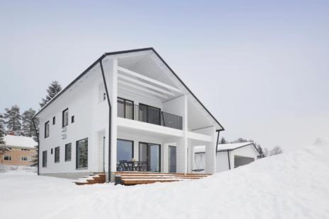 This modern white home was built near the center of a lively small town. The house was built quickly with the help of careful planning, solid log technology, and local builders.