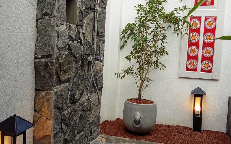 Indulge in a serene outdoor bathroom experience, surrounded by natural stone and tropical greenery.