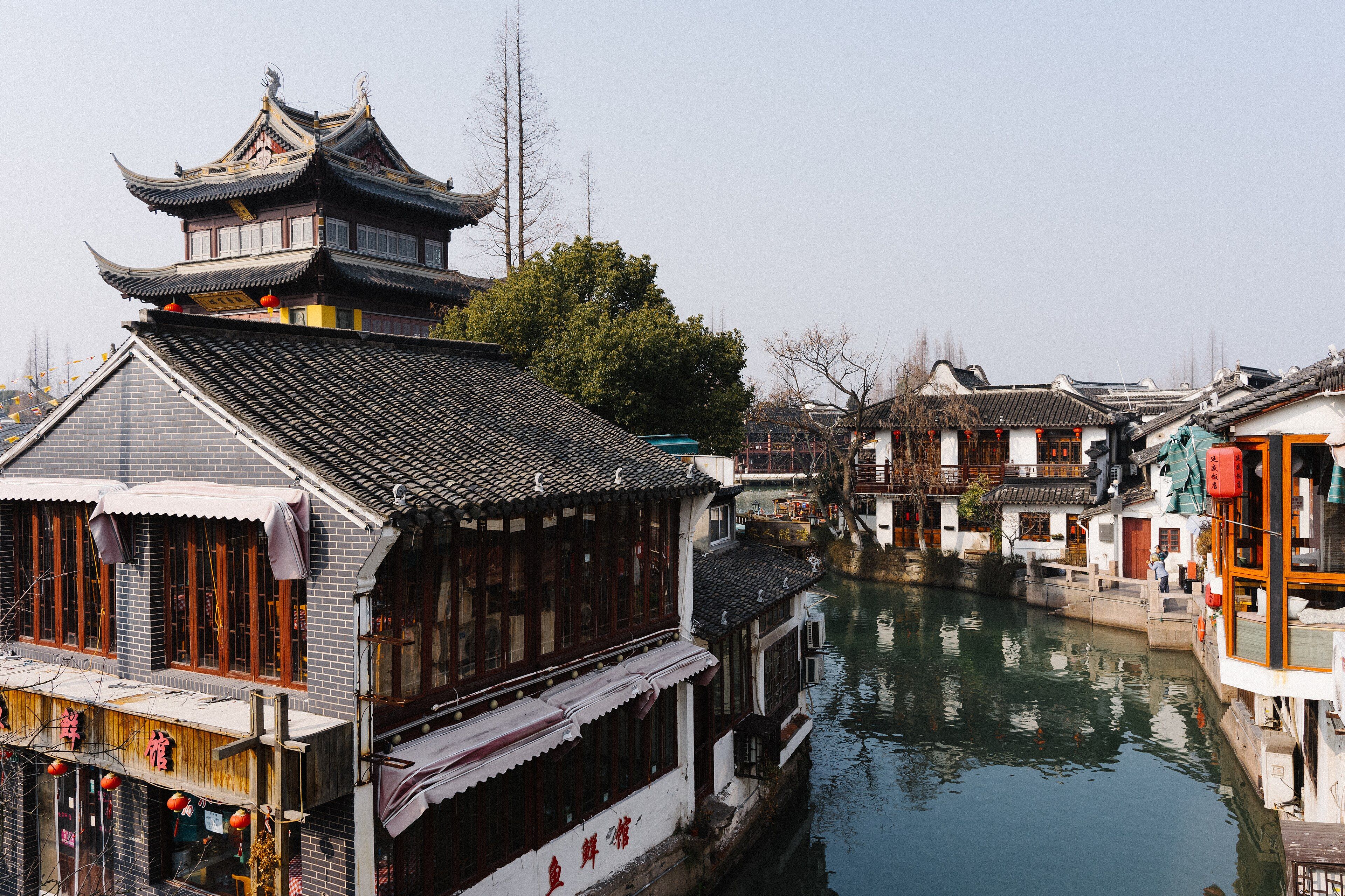 Old houses and a pagoda-roofed tower beside a canal in Zhujiajiao water town