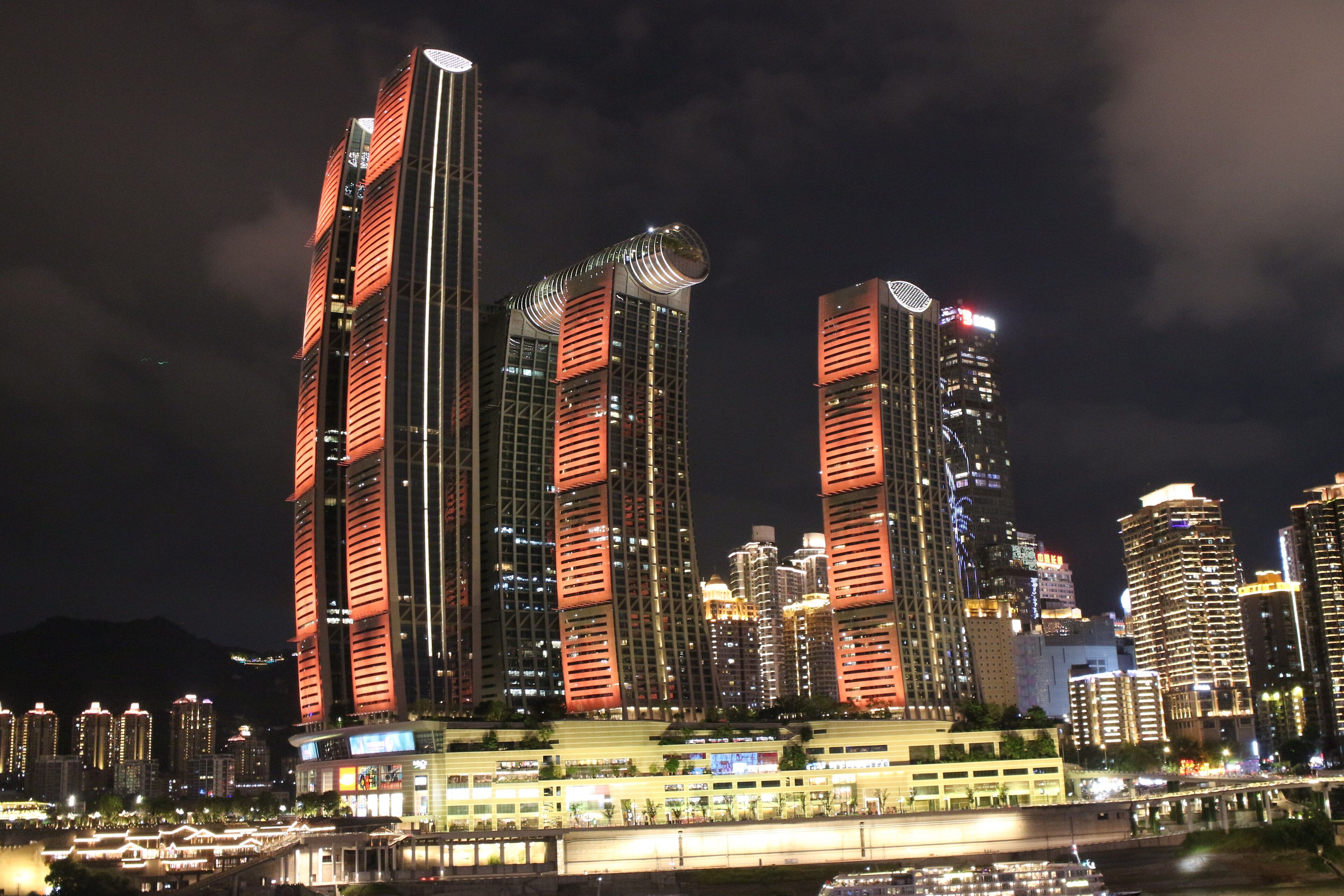 The Raffles City towers and their sky bridge lit up above Chaotianmen at night