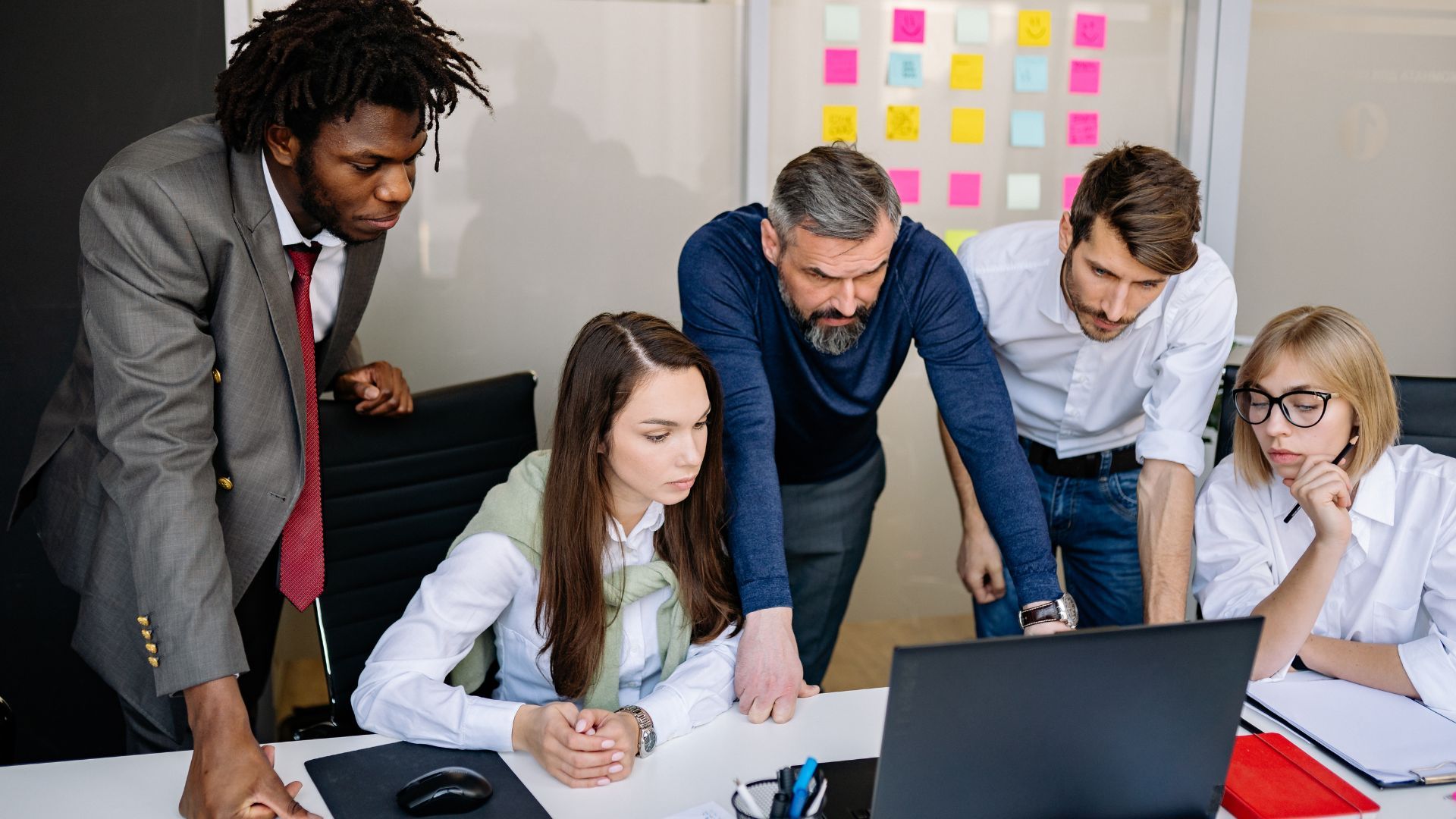 A team of 5 people is staring at a notebook screen