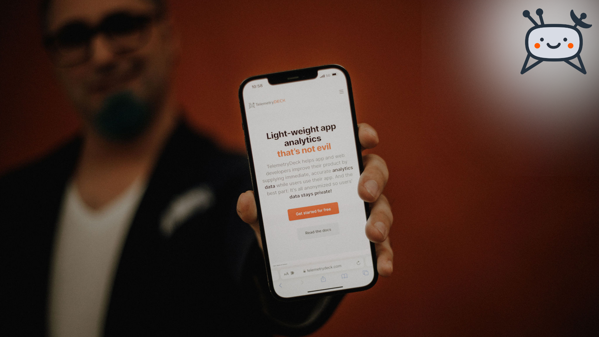 Daniel, one of the founders of TelemetryDeck holds up a phone into the camera, showing the TelemetryDeck website. The focus is on the phone, everything behind it is blurry.