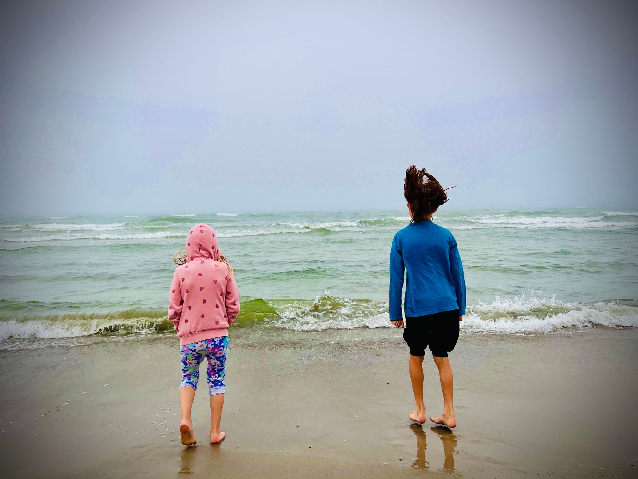 Two kids on the beach. Stormy weather.