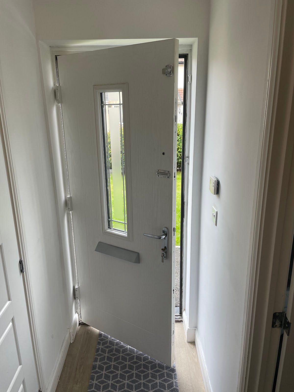 White composite front door with chrome handle viewed from a hallway, the type of door you might be locked out of