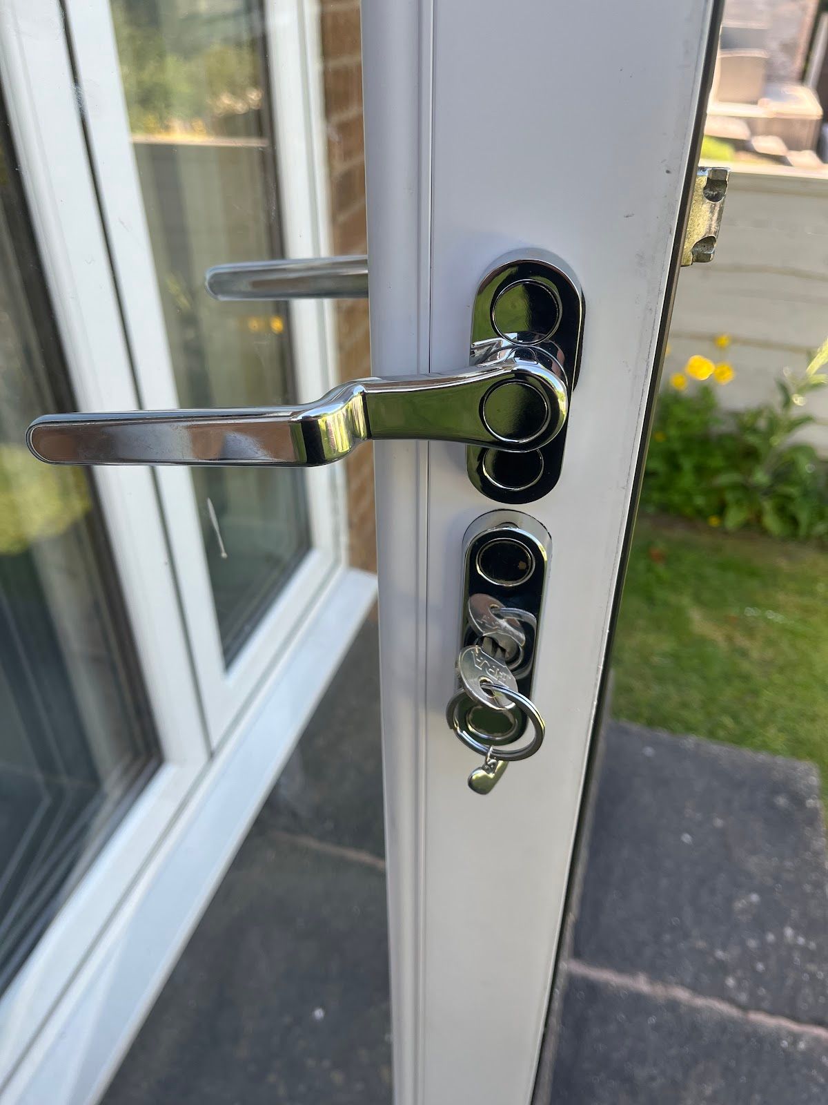 Chrome handle with keys in a white uPVC door lock, showing a typical uPVC locking mechanism