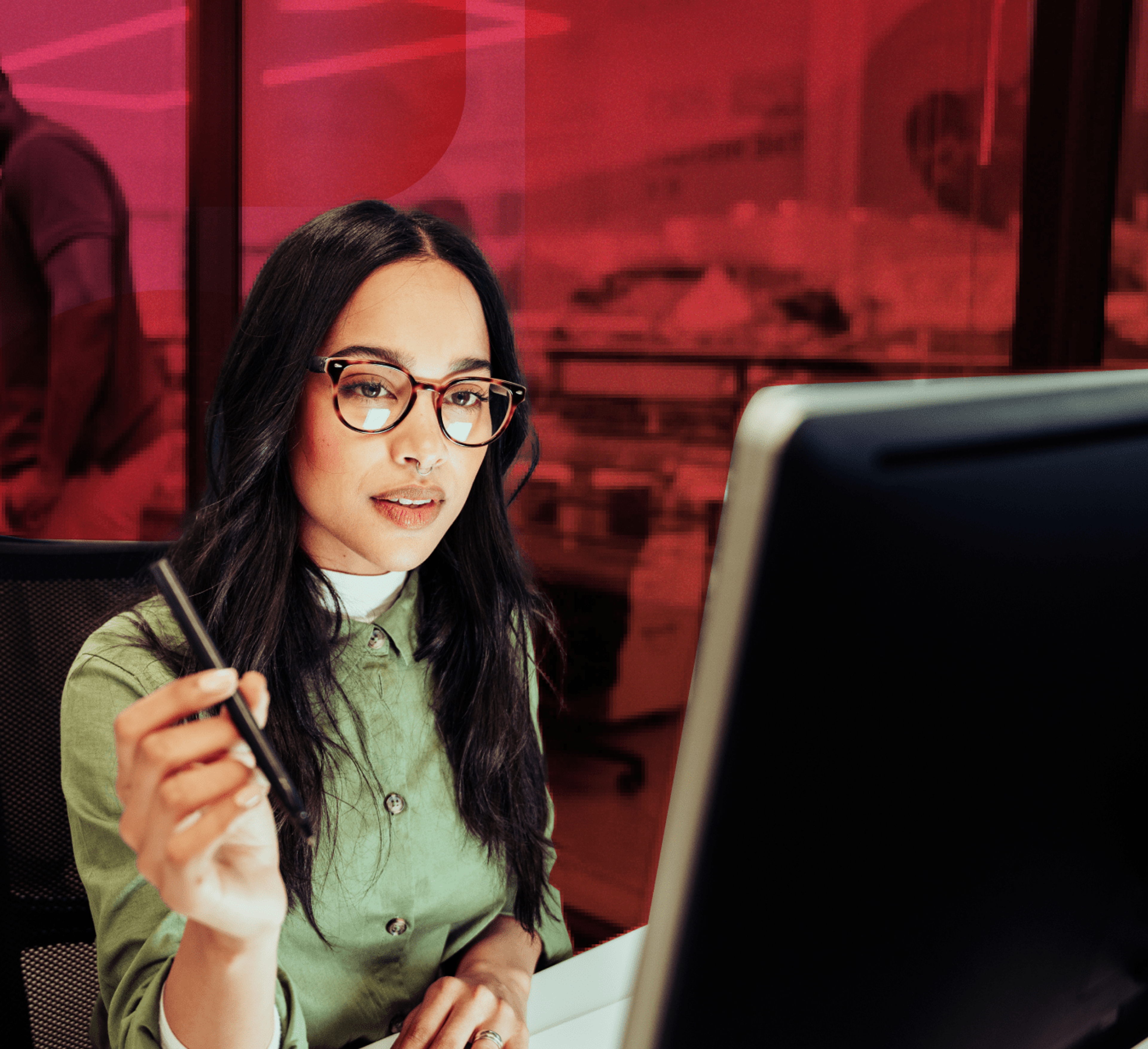woman looking at a computer screen with a pen