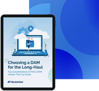 eBook cover of the choosing a digital asset management (DAM) for the long-haul, top considerations to find a DAM vendor that can scale with the mediavalet logo, with an animated laptop with three people standing around it with clouds and gears on a geometrics blue faded background