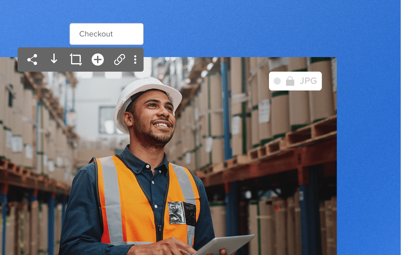 Man working in a warehouse surrounded by boxes wearing an orange vest and white hardhat holding a tablet smiling, image shows checkout feature and jpg file type