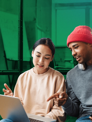 woman and man working on laptop to learn what the differences are between DAMand CMS, on a green background.