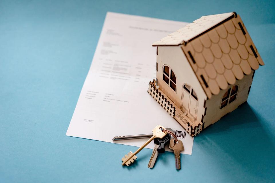 Casa em miniatura, chaves e documento representando titularidade imobiliária