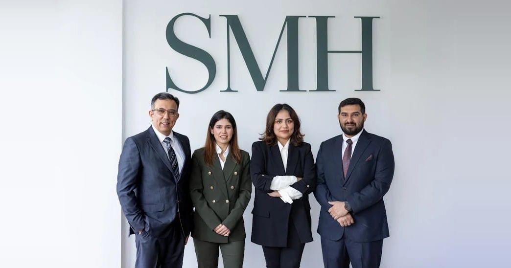 The SMH Group team standing in front of the SMH sign