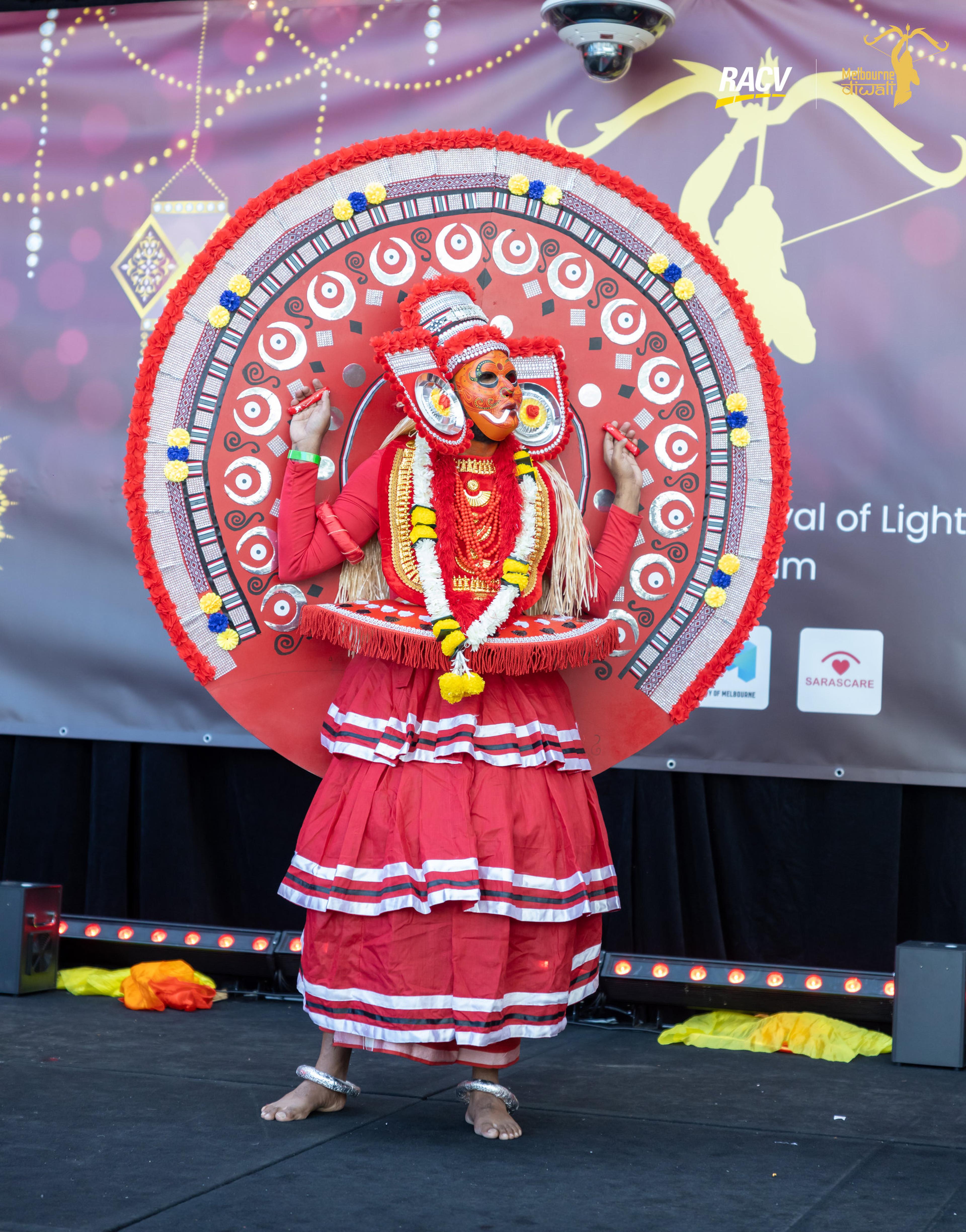 A Theyyam performer in an elaborate red headdress on the main stage at Melbourne Diwali
