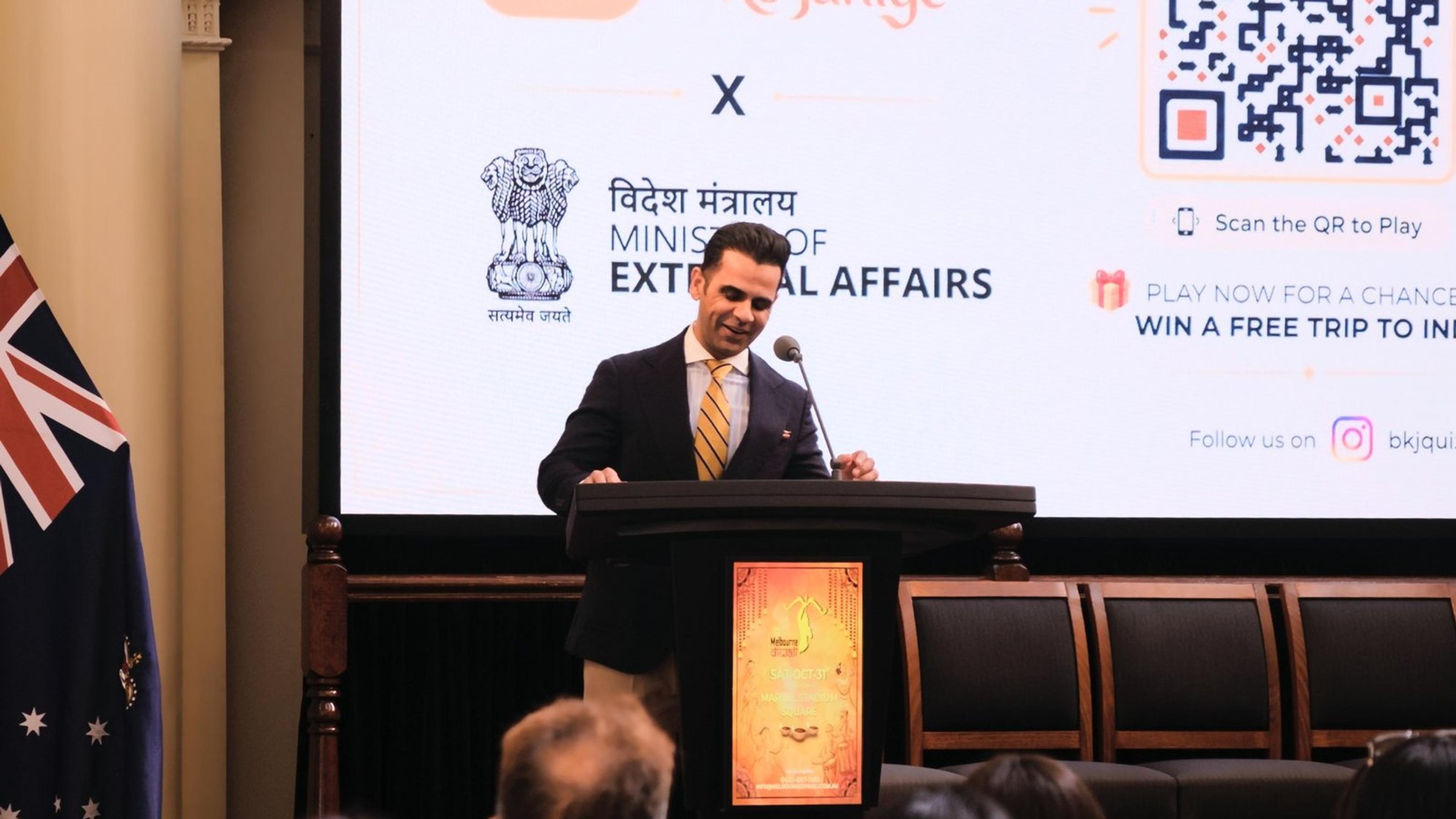 Pankaj Malhotra speaking at a lectern in Queen's Hall, Parliament House, in front of a Bharat Ko Janiye slide