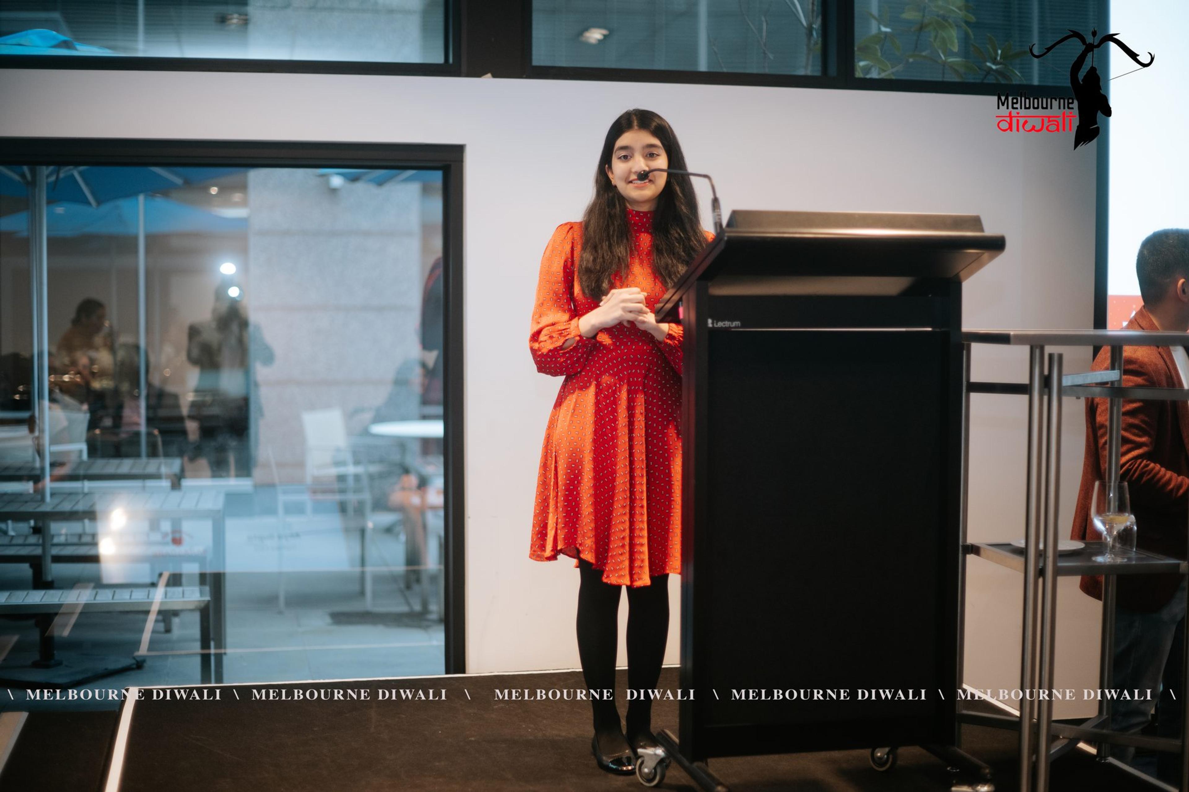 Anya Gupta, the MC, welcomes guests from the lectern
