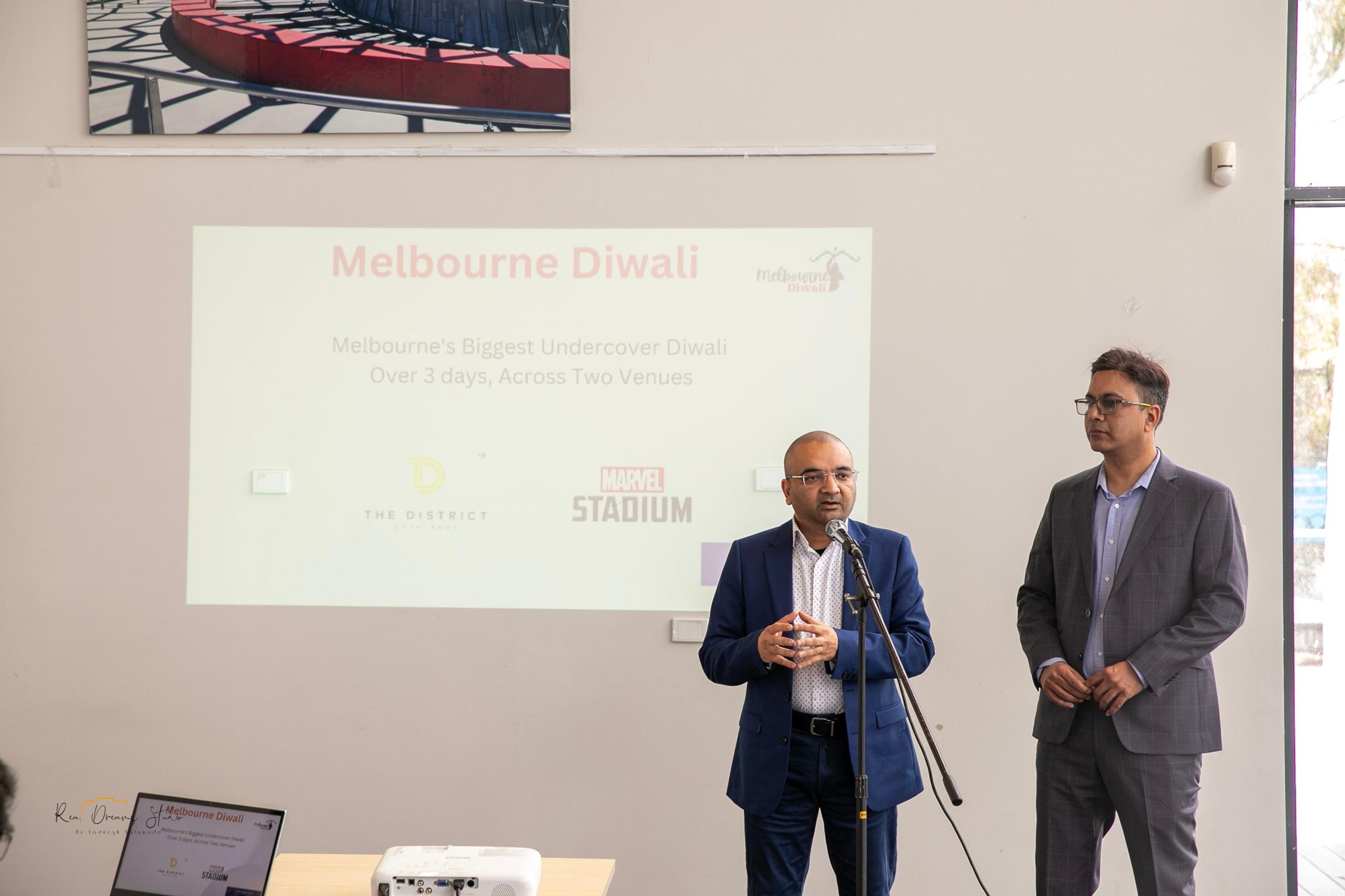 Two presenters beside the slide 'Melbourne's Biggest Undercover Diwali, over 3 days, across two venues'