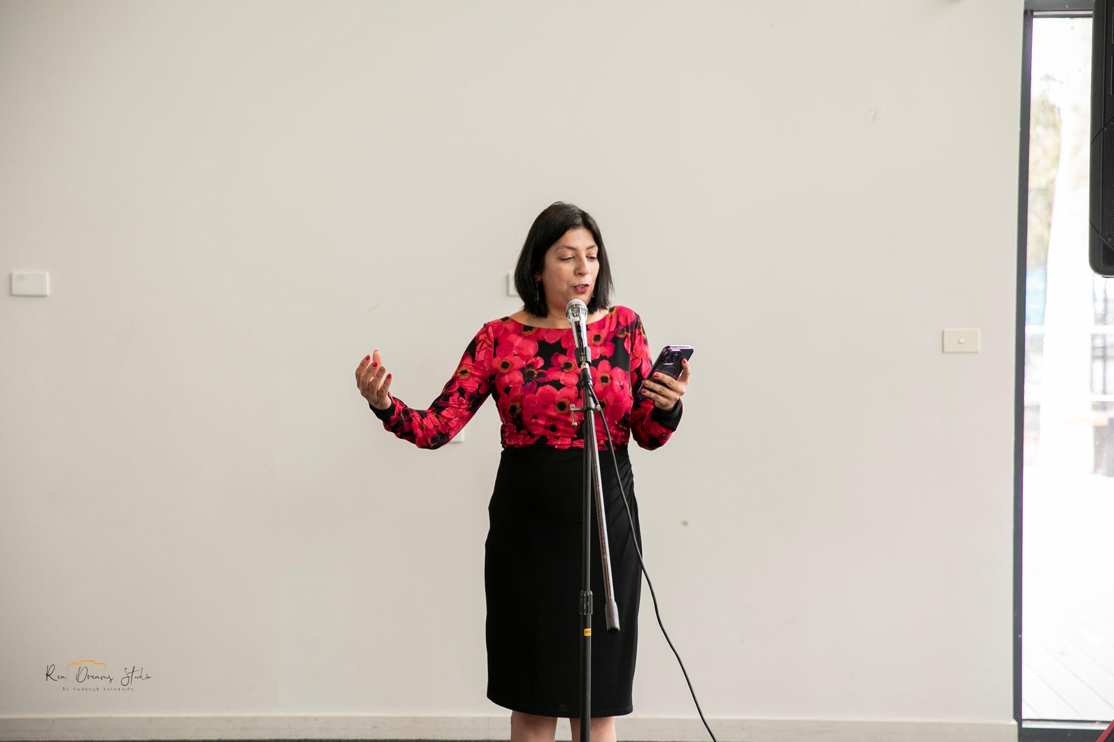 Anu Bhardwaj, CEO of Melbourne Diwali, reads her address from her phone at the microphone