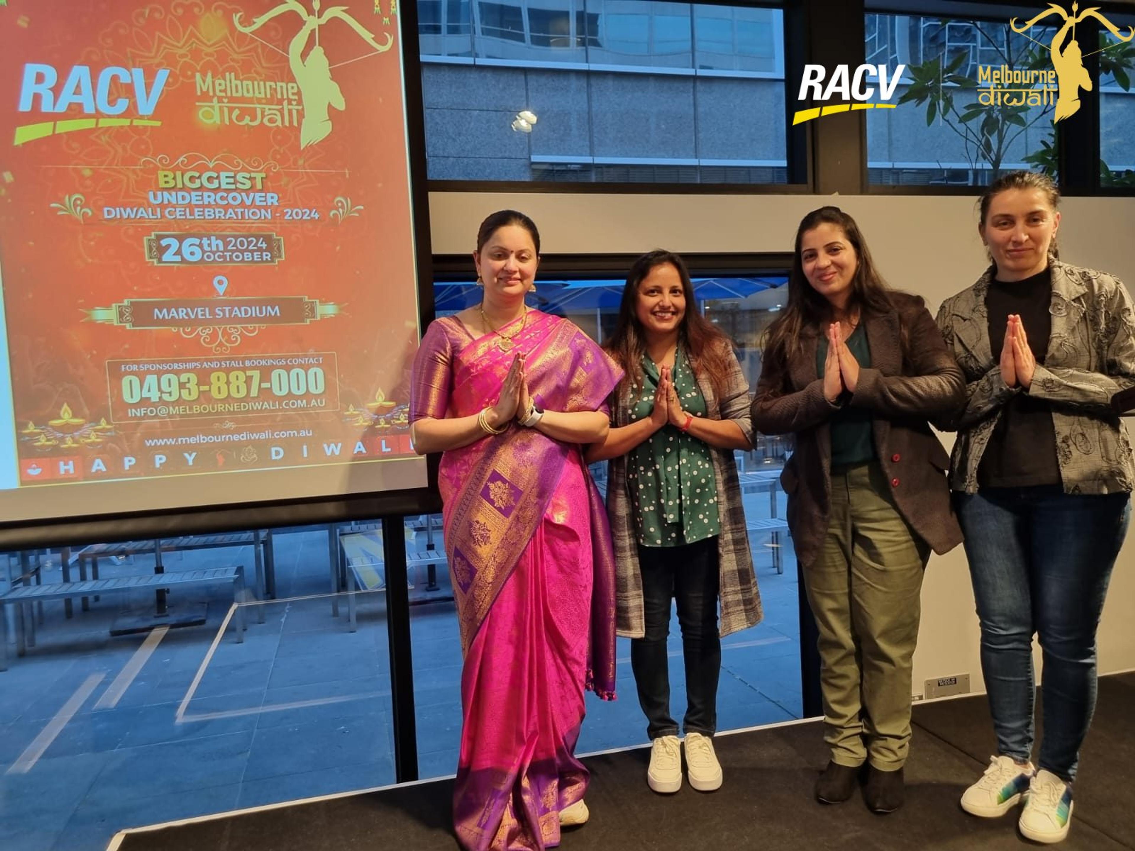 Four guests with palms joined in namaste in front of the festival poster