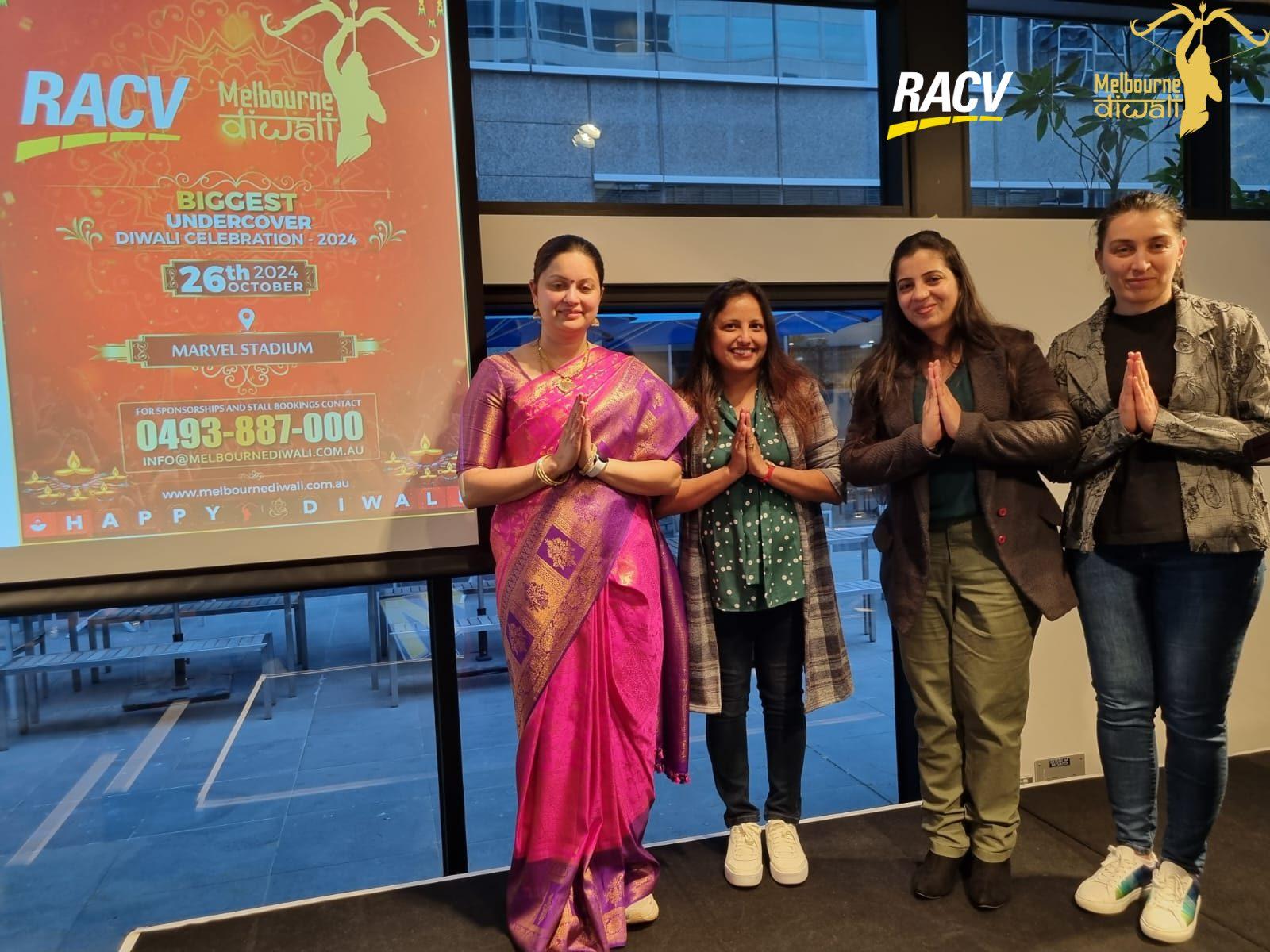 Four guests with palms joined in namaste in front of the festival poster