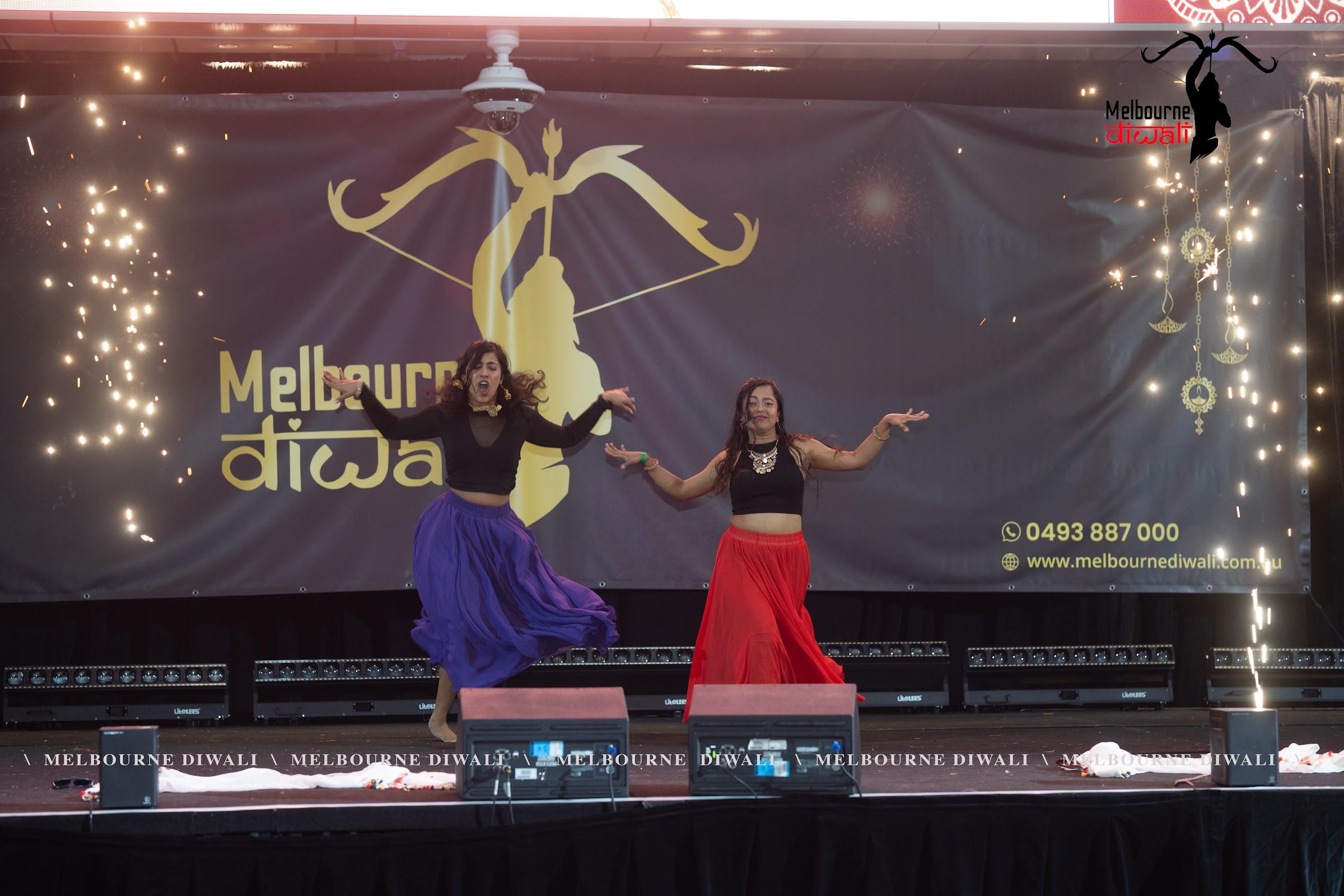Two dancers perform between columns of stage pyrotechnics at Melbourne Diwali 2025