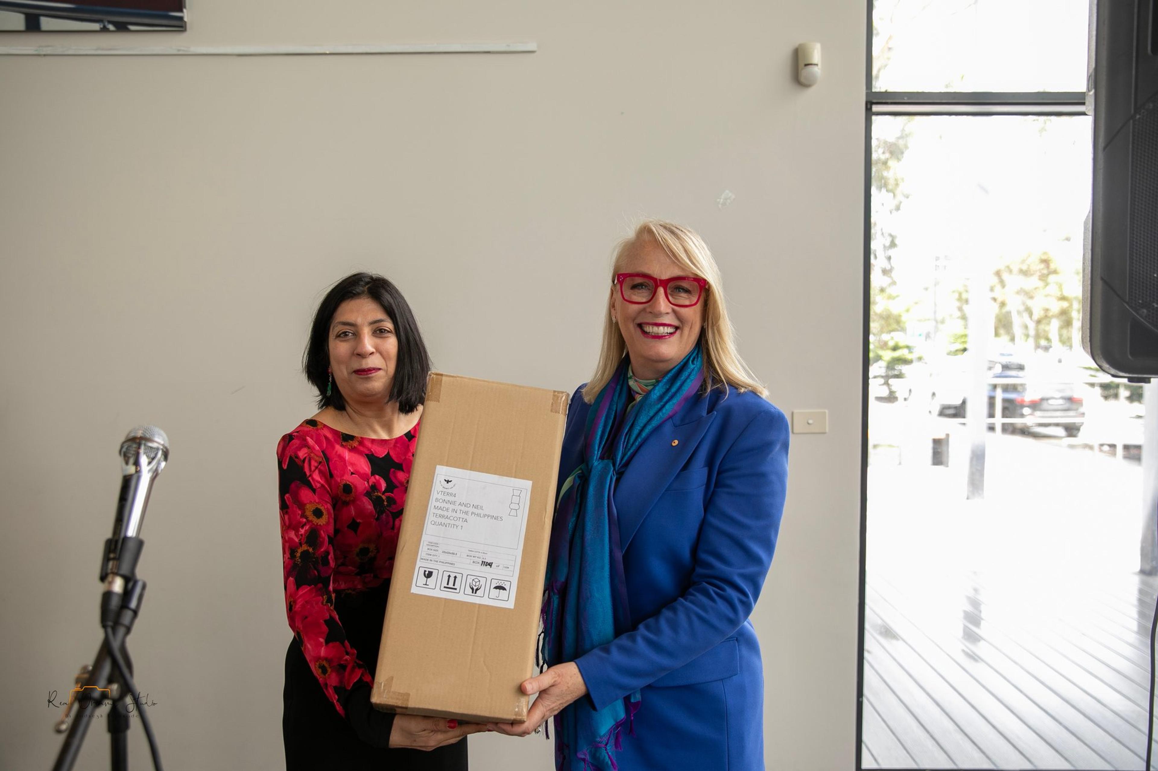 A boxed gift is presented at the front of the room