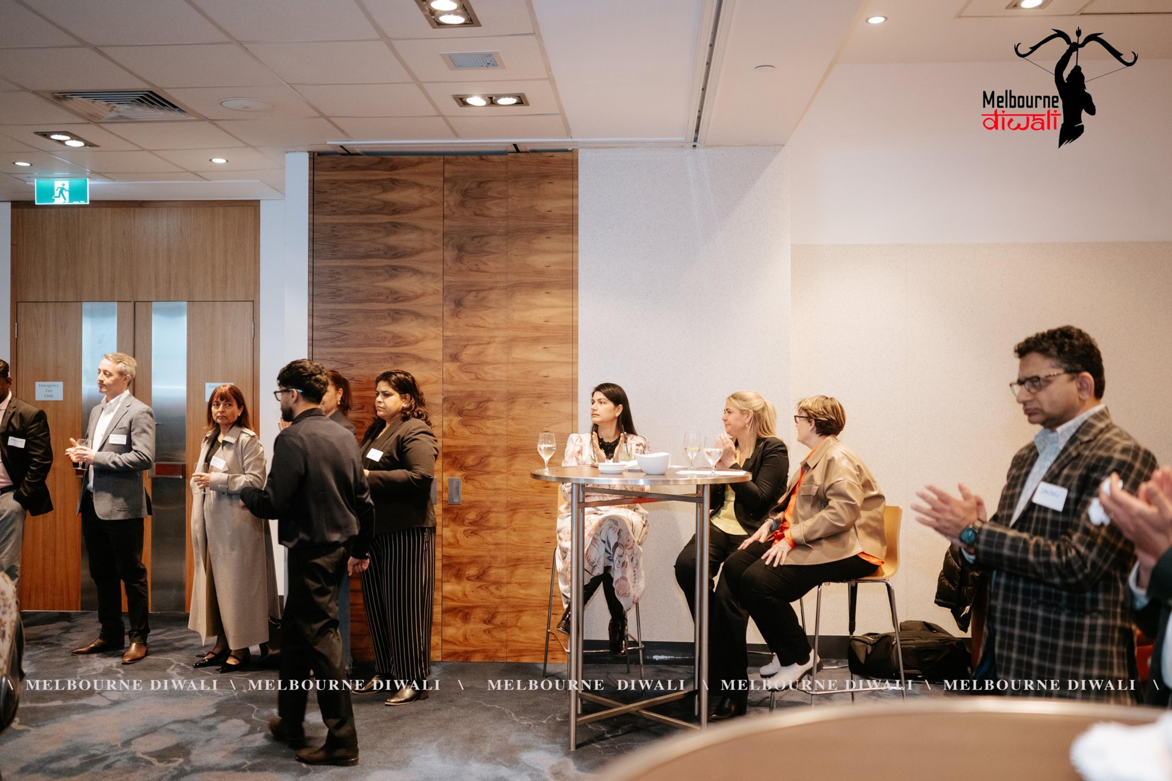Guests stand and sit at high tables along the side of the room
