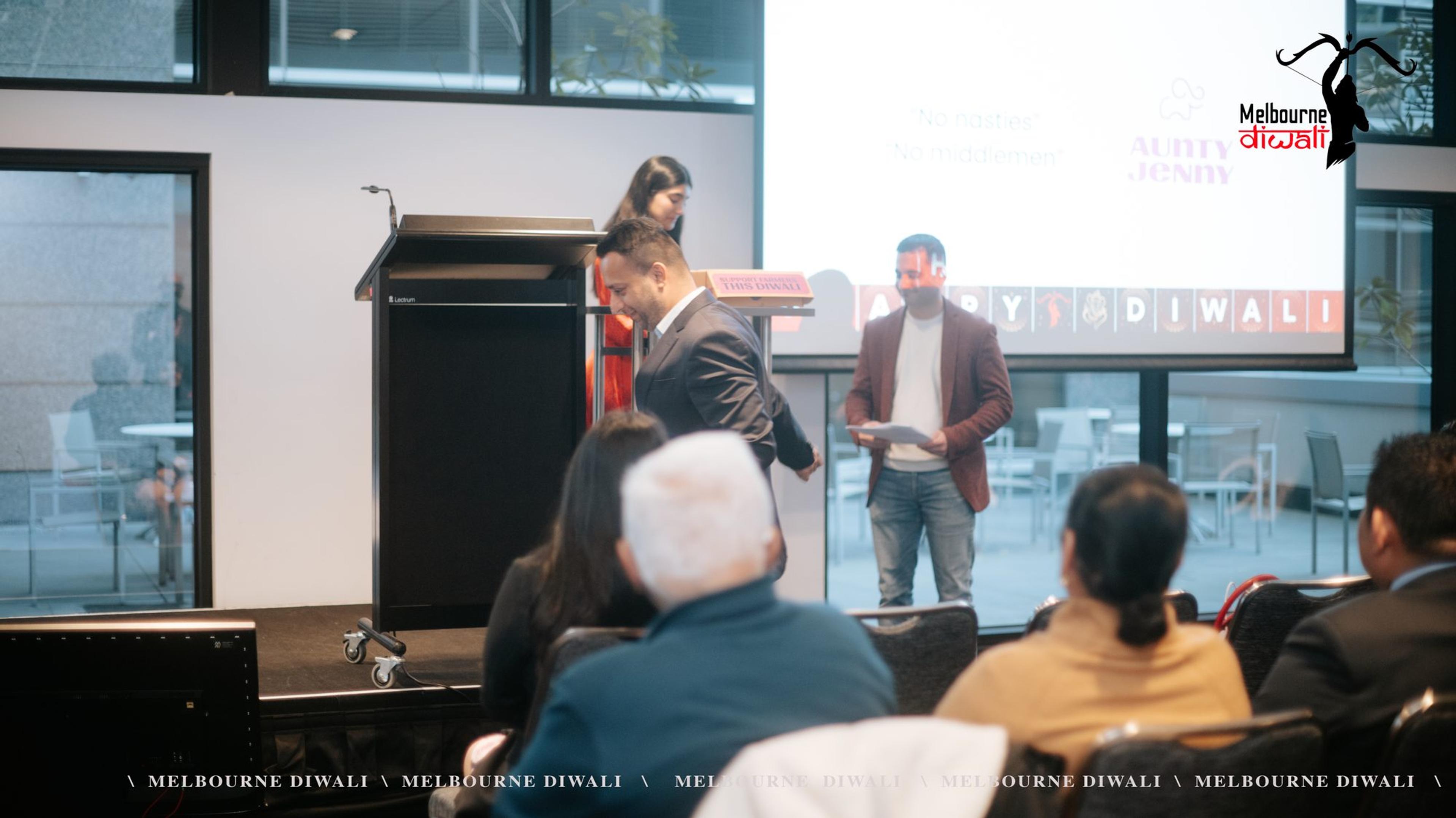 The Aunty Jenny presentation at the lectern, with guests seated in the foreground