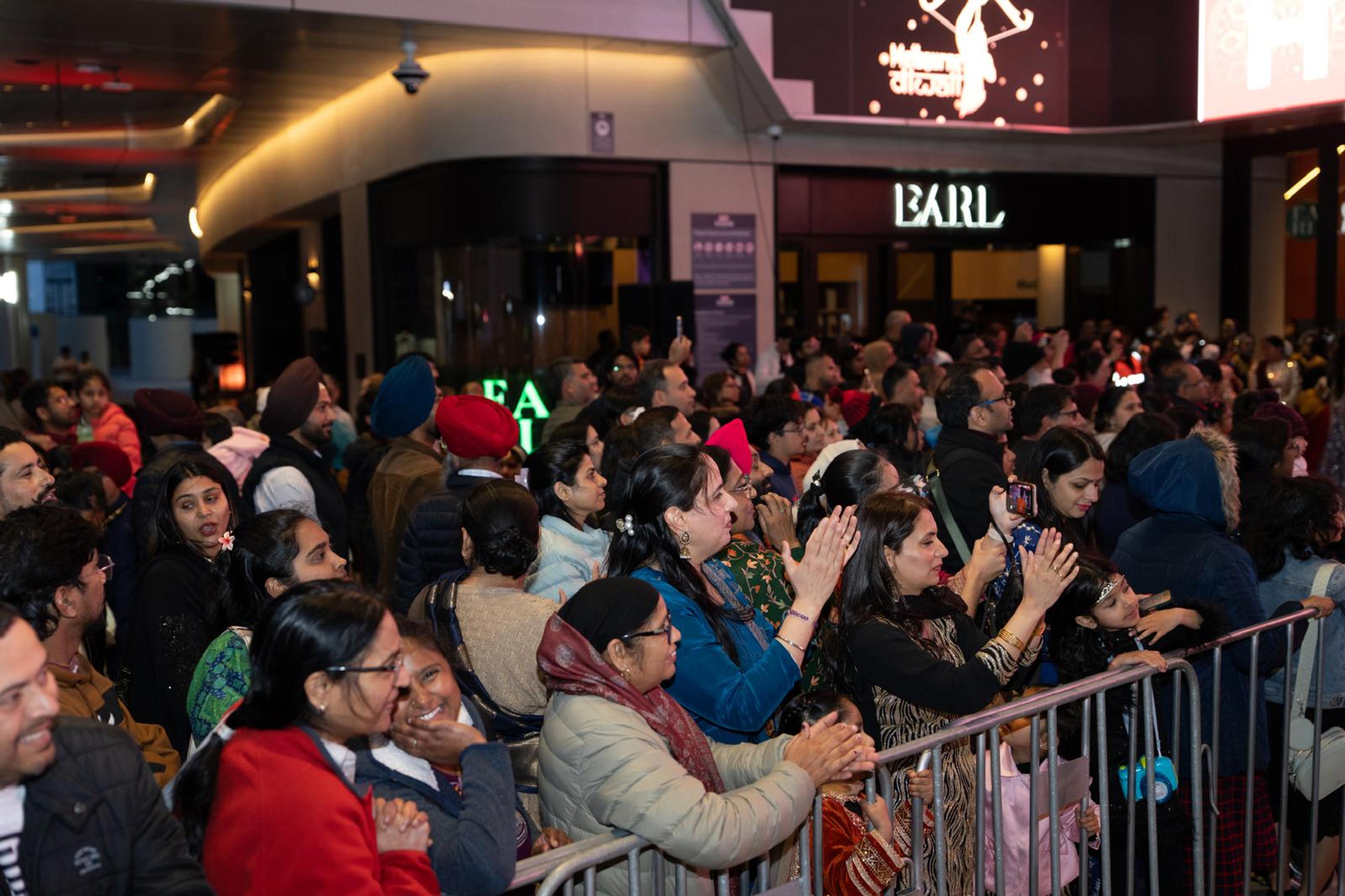 A packed evening crowd applauds a performance at Melbourne Diwali 2025