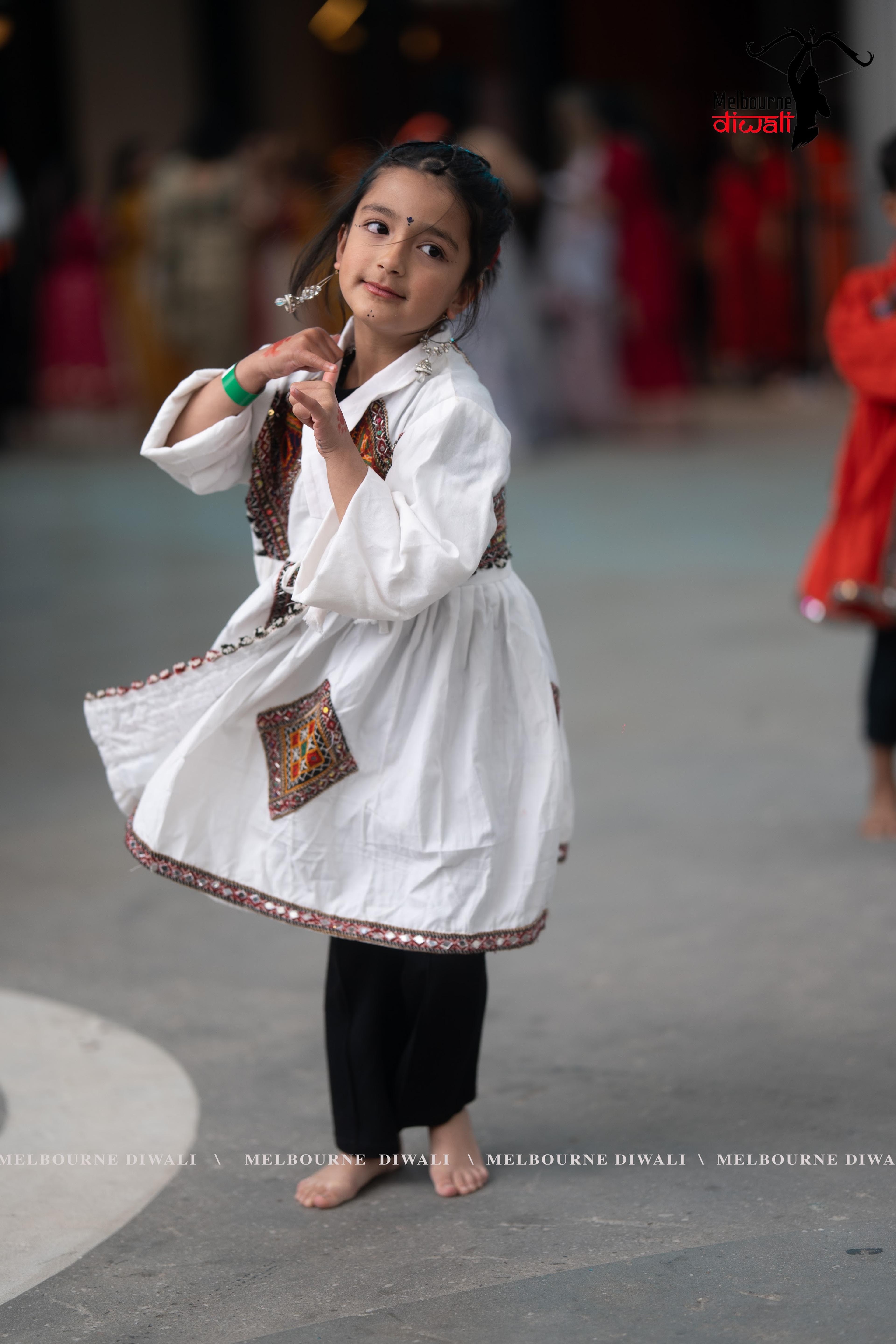 A young festival-goer in traditional white and red dress at Melbourne Diwali 2025