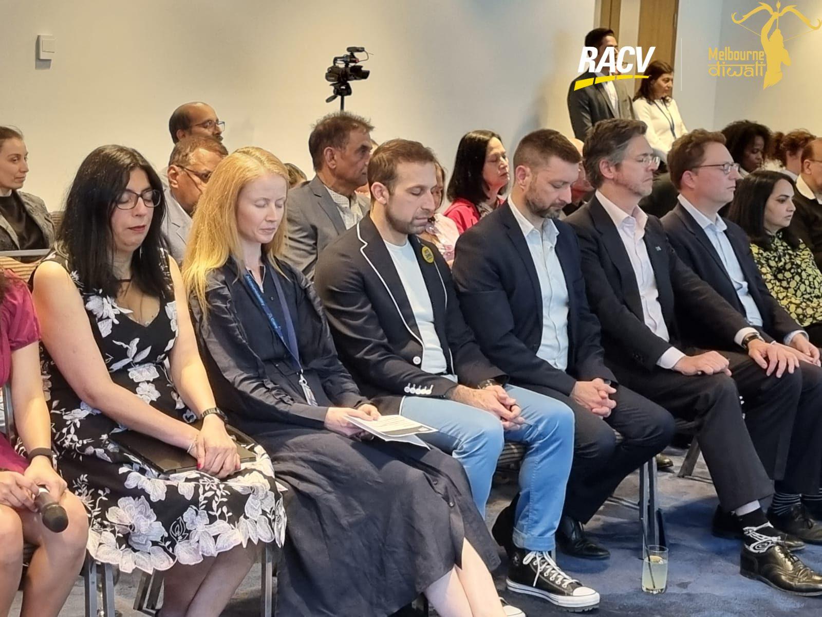 The front row of guests, one holding a printed programme