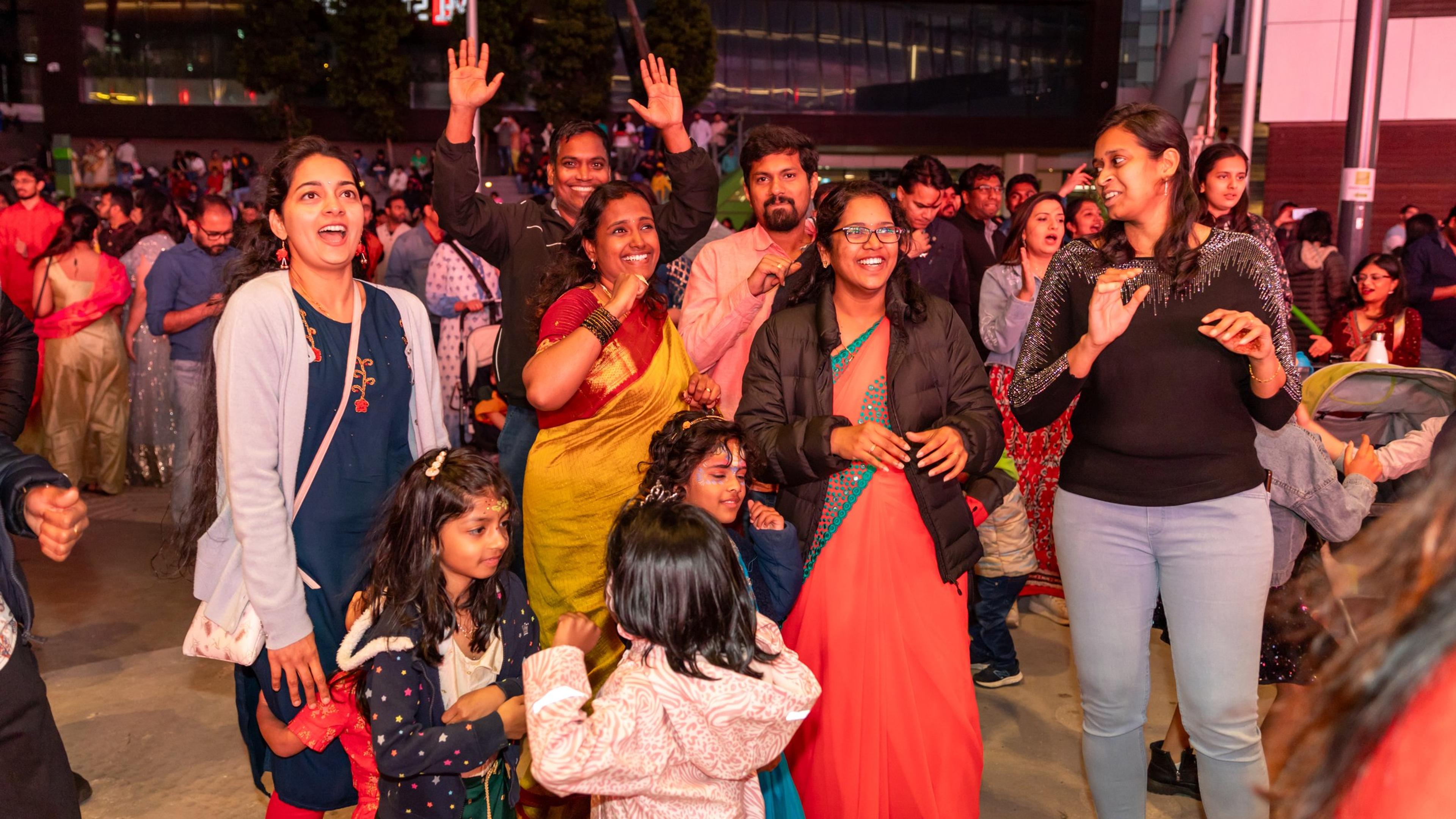 Families dancing together in the evening crowd at Melbourne Diwali