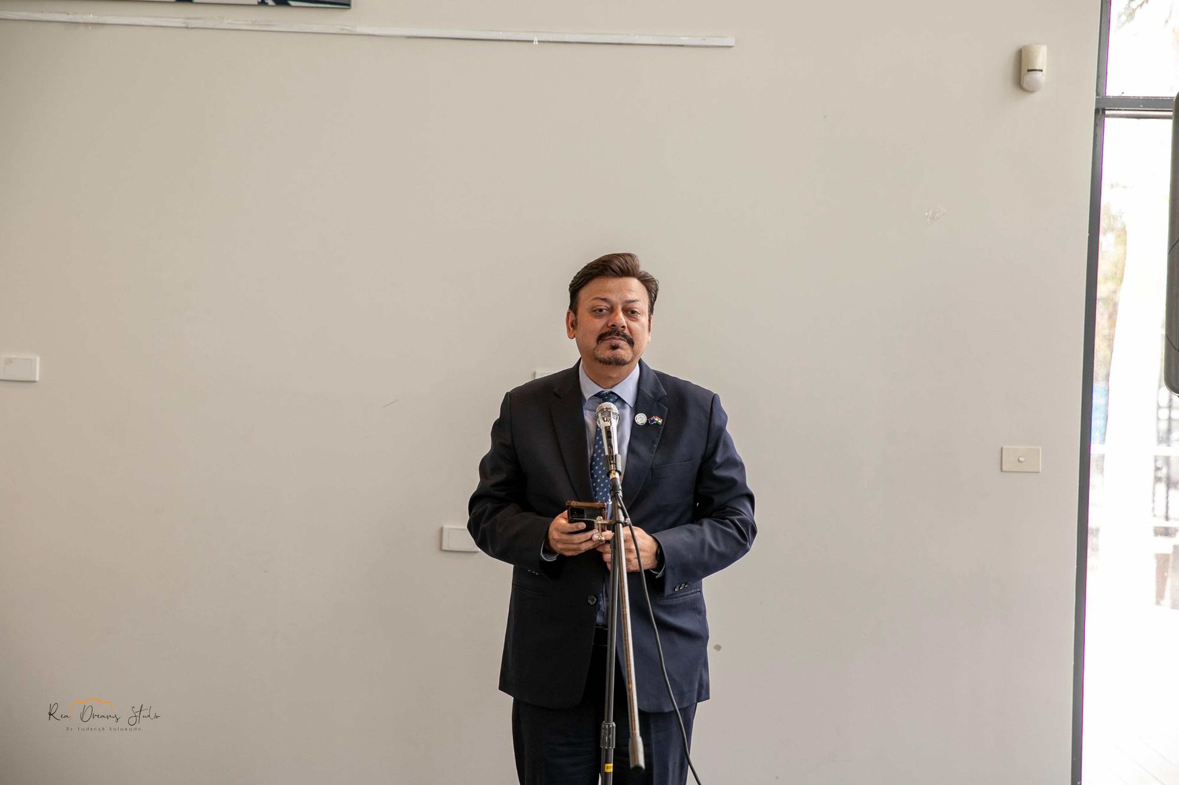 A guest in a dark suit speaks at the microphone