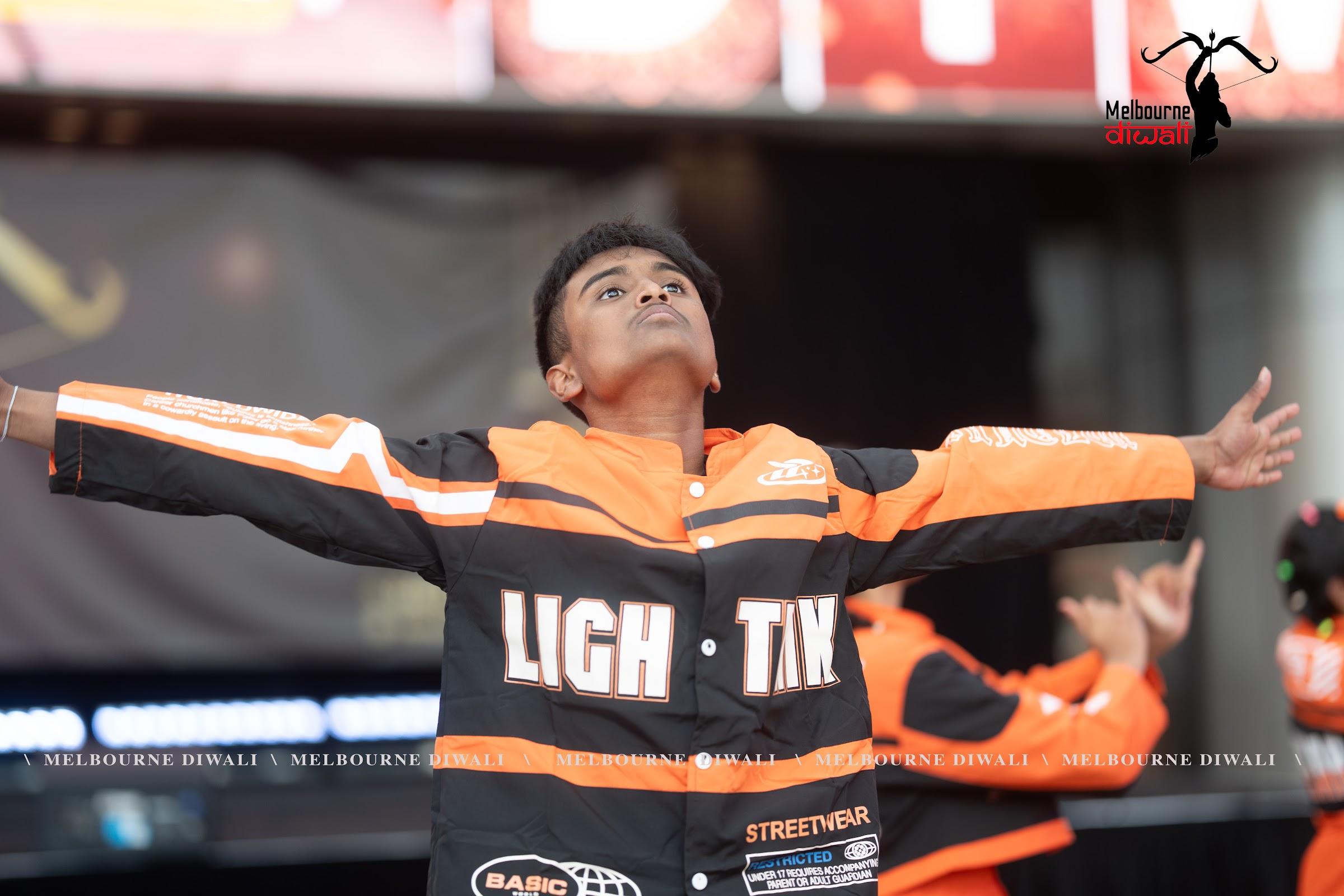 A young dancer throws their arms wide at the end of a routine at Melbourne Diwali 2025