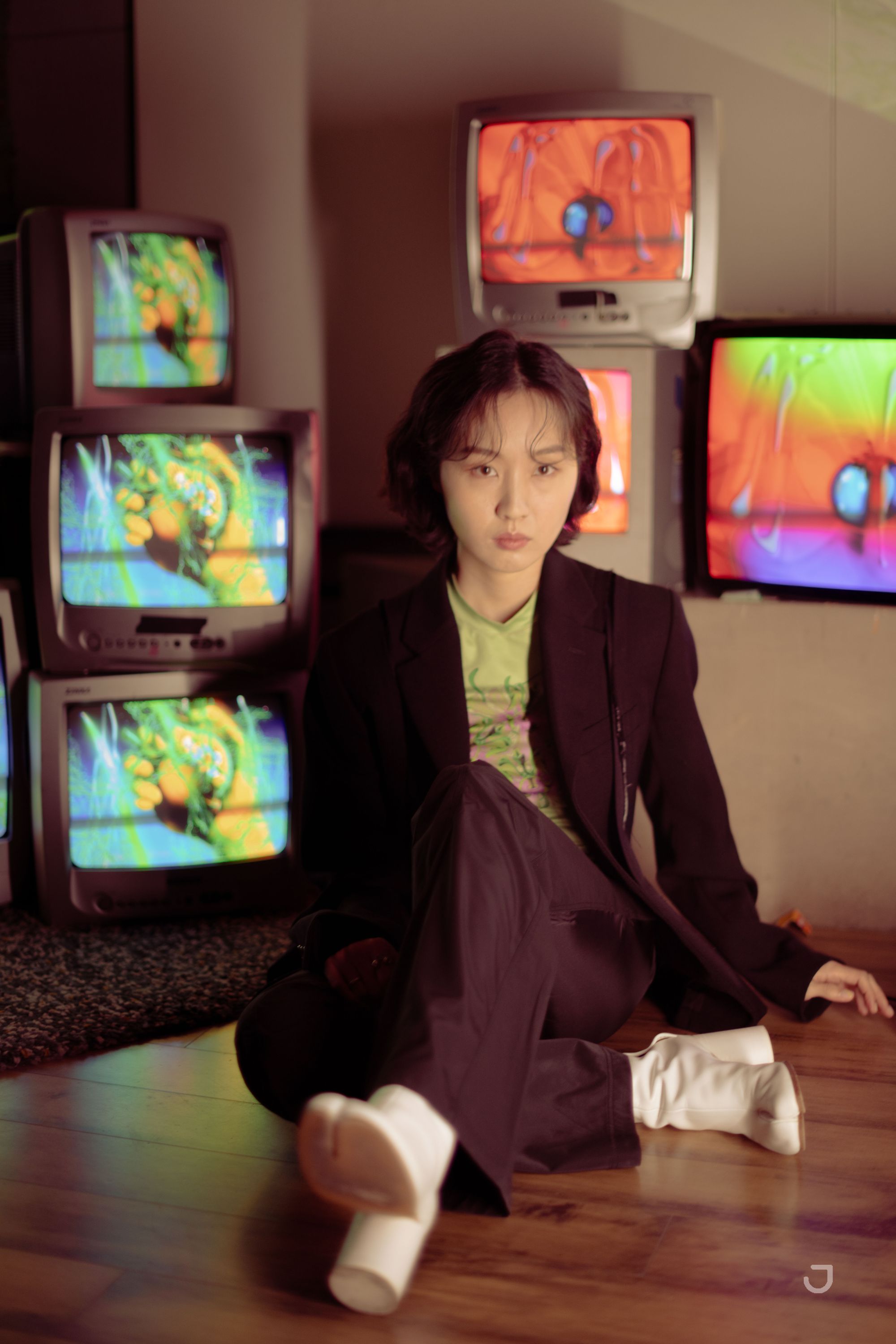 Artist Ram Han with flowers in front of retro TVs with her work on them