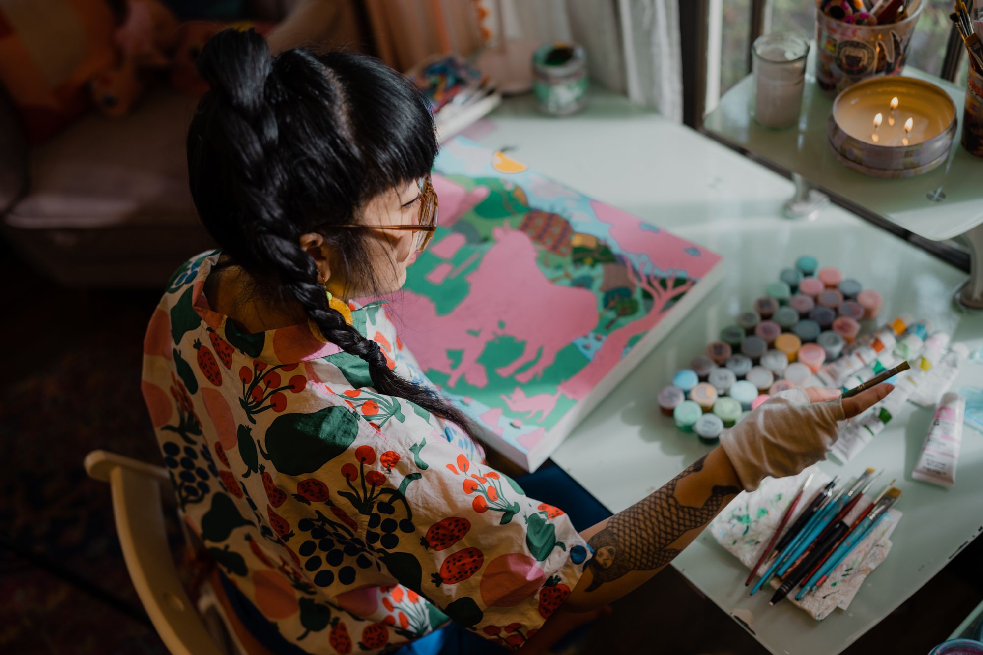 Candid photograph of painter and illustrator Kristen Liu-Wong working on a new painting in her home studio.