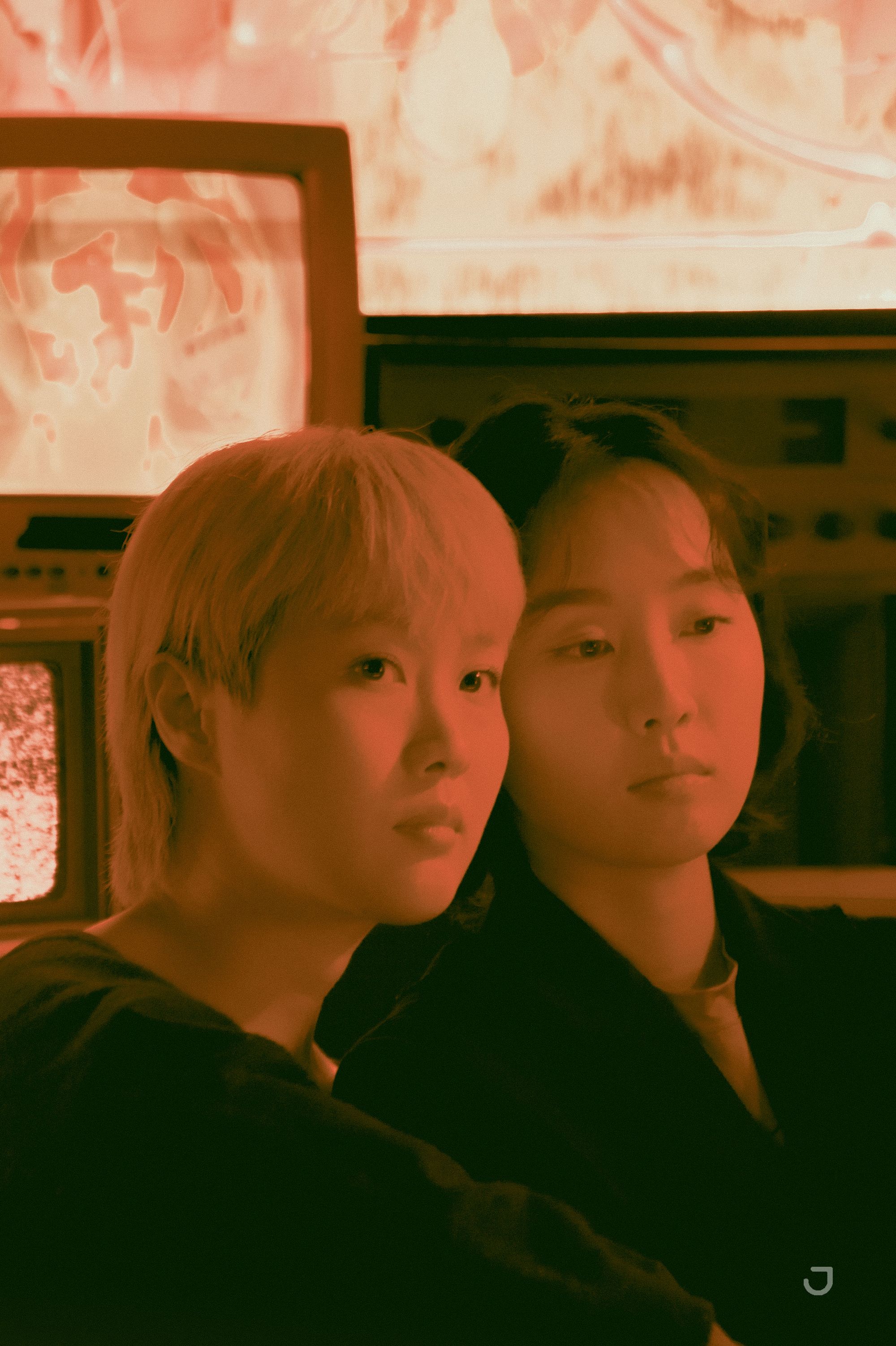 Artist Ram Han and her twin sister sit together under red light