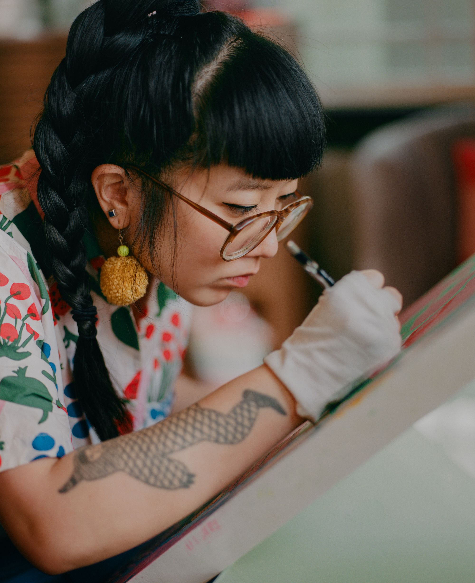 Candid photograph of painter and illustrator Kristen Liu-Wong working on a new painting in her home studio.