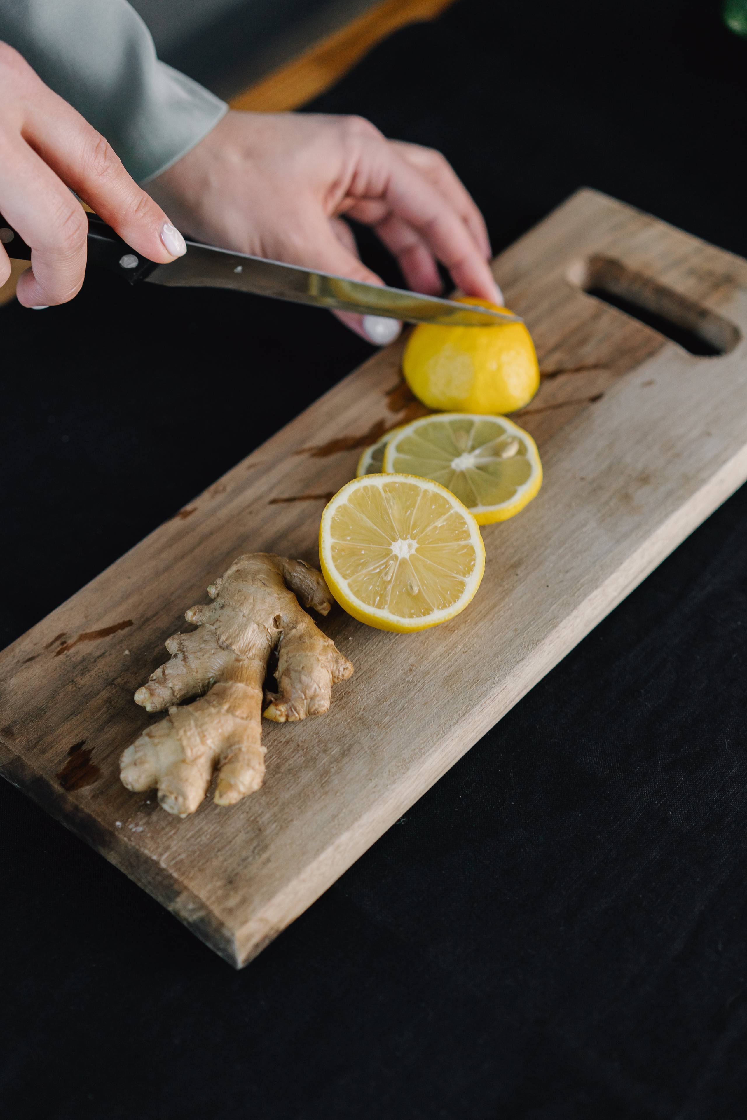 ginger and lemon being cut on a cutting board