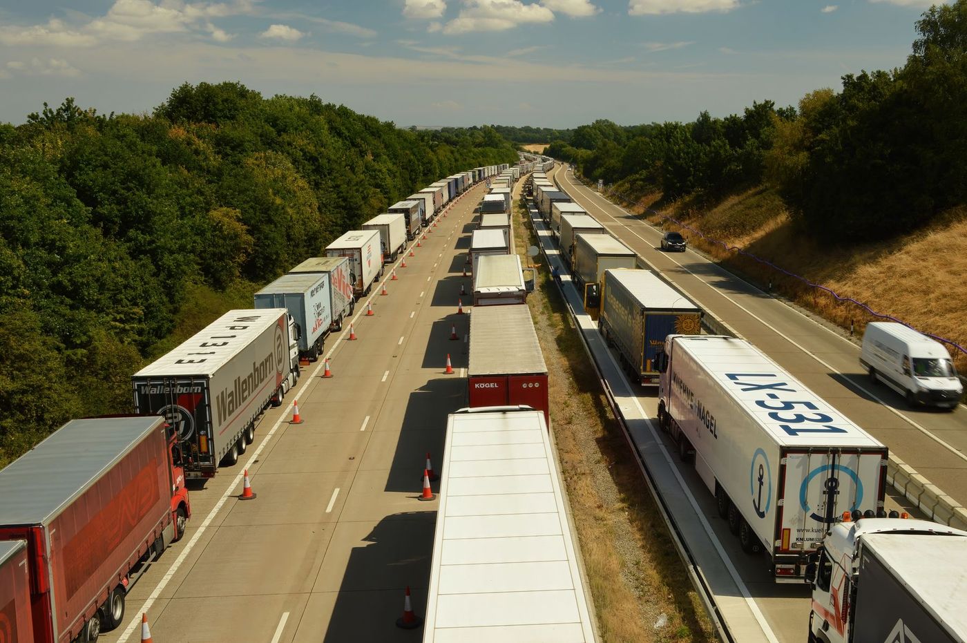Vue aérienne de files de camions sur une autoroute à deux chaussées.