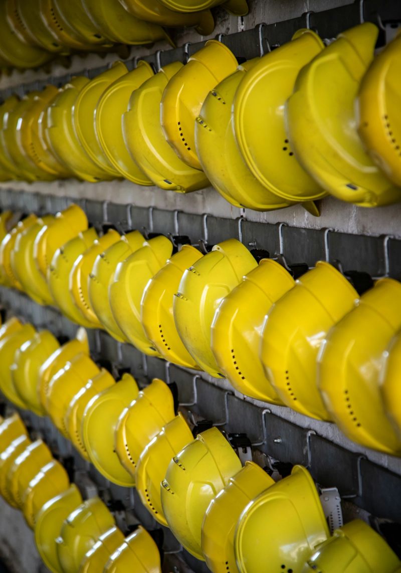 Rangées de casques de chantier jaunes accrochés à un support mural