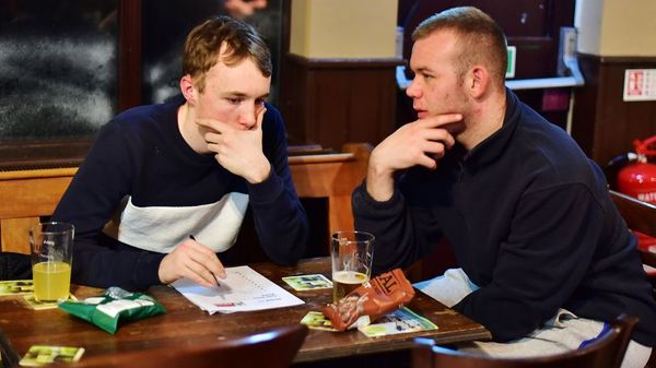Two men completing a pub quiz