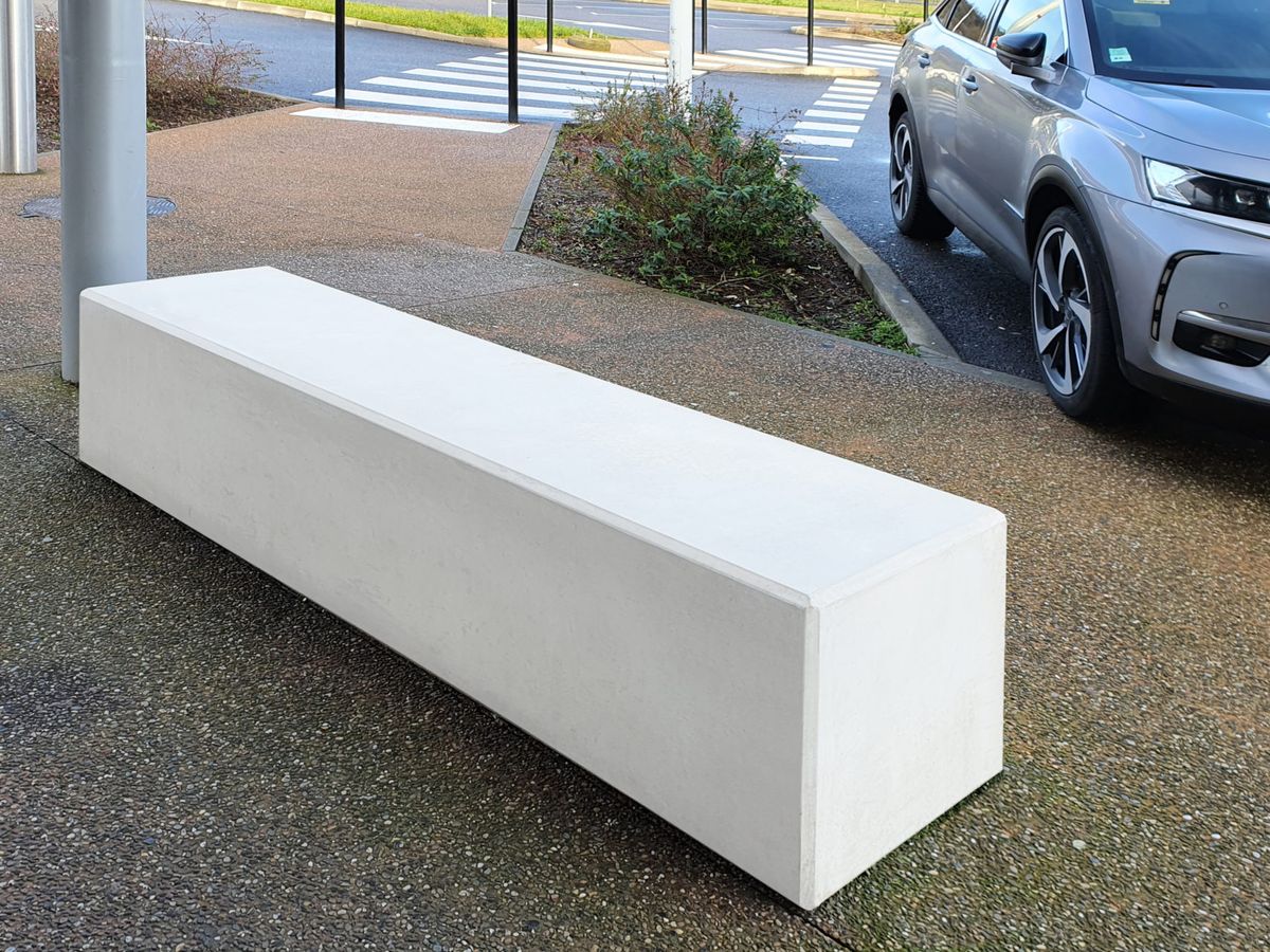 Banc en béton installé dans un aménagement urbain