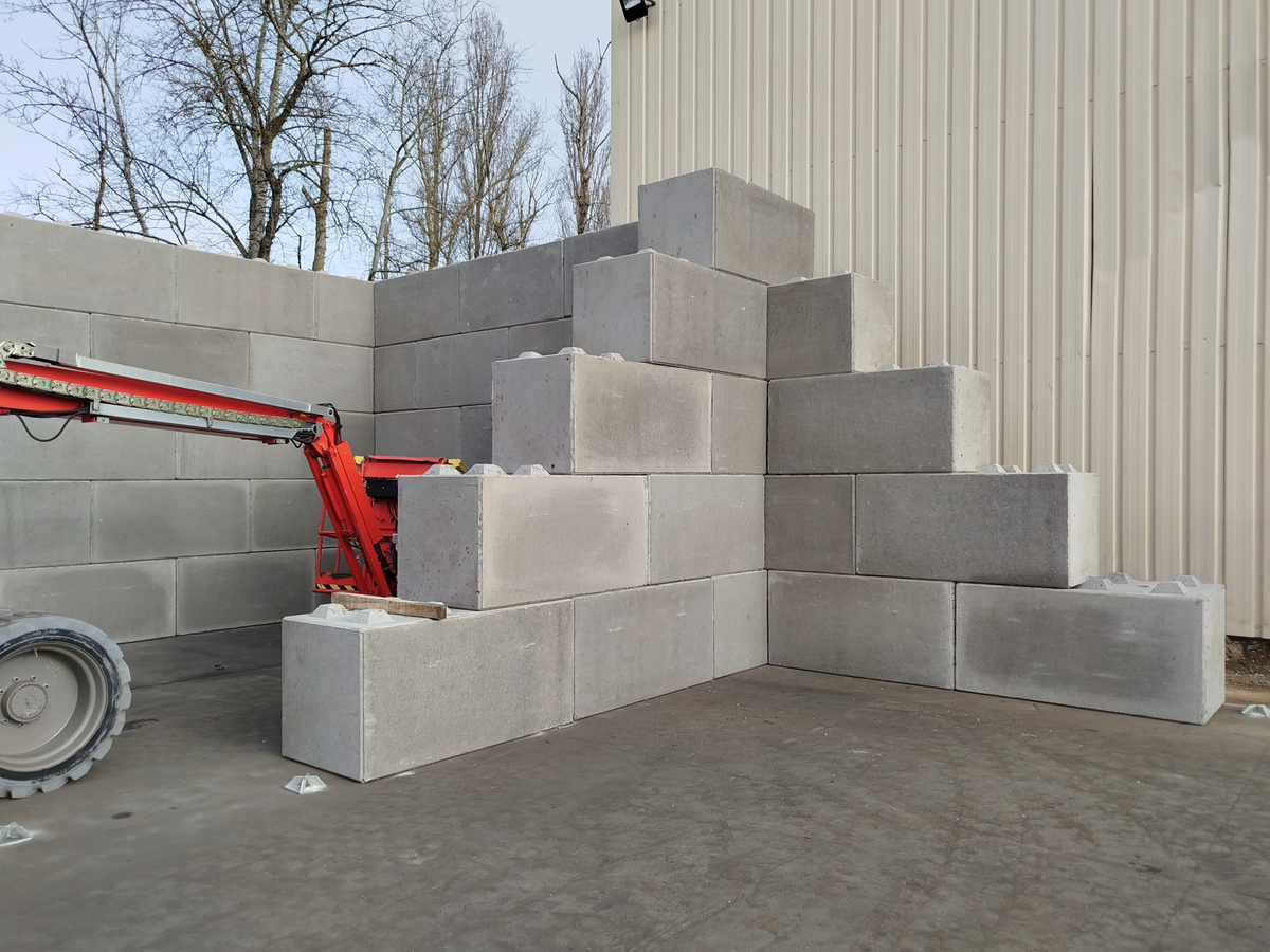 Blocs béton gris en cours d'installation sur un chantier industriel