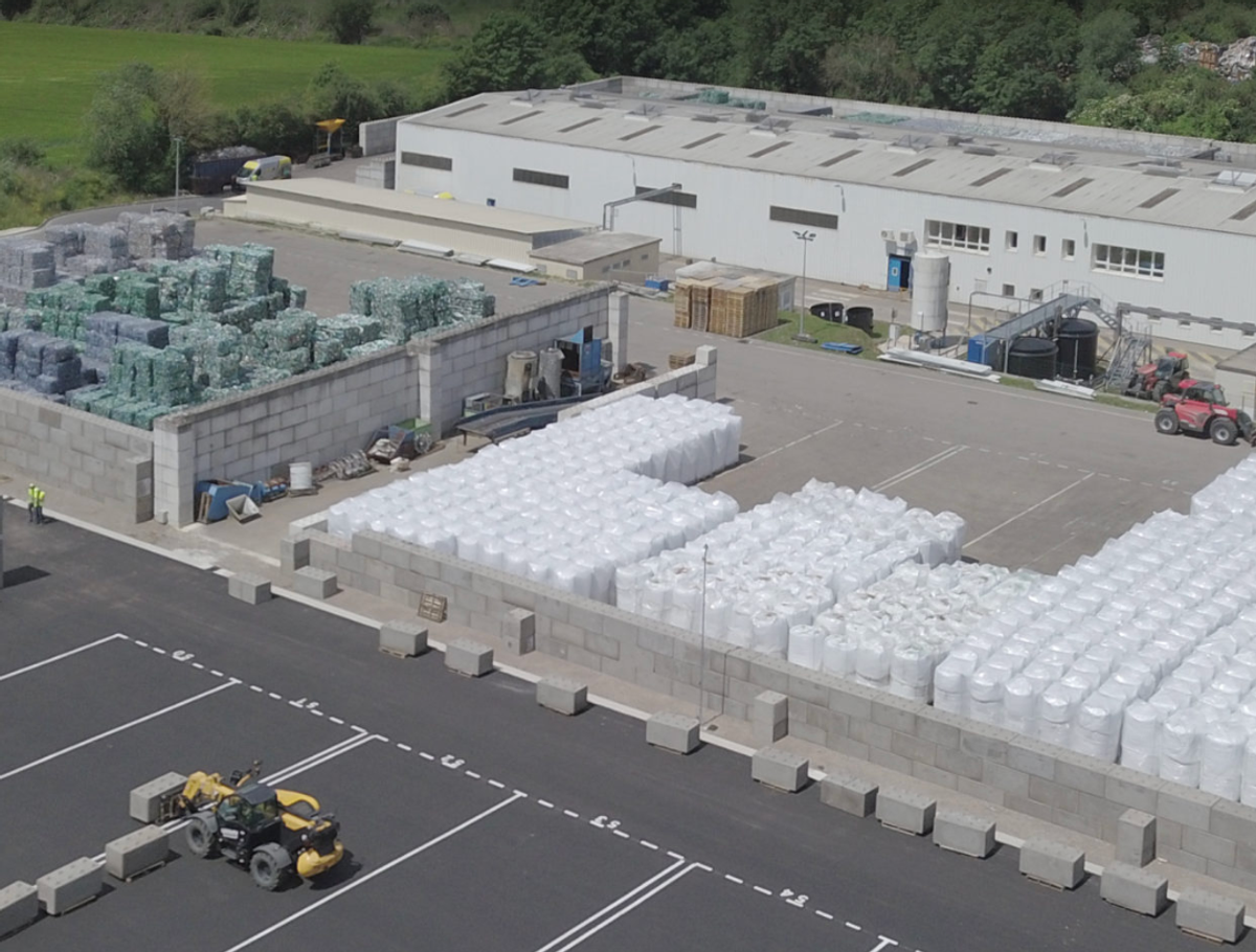 Site industriel avec plusieurs alvéoles de stockage délimitées en blocs béton et circulation d'engins