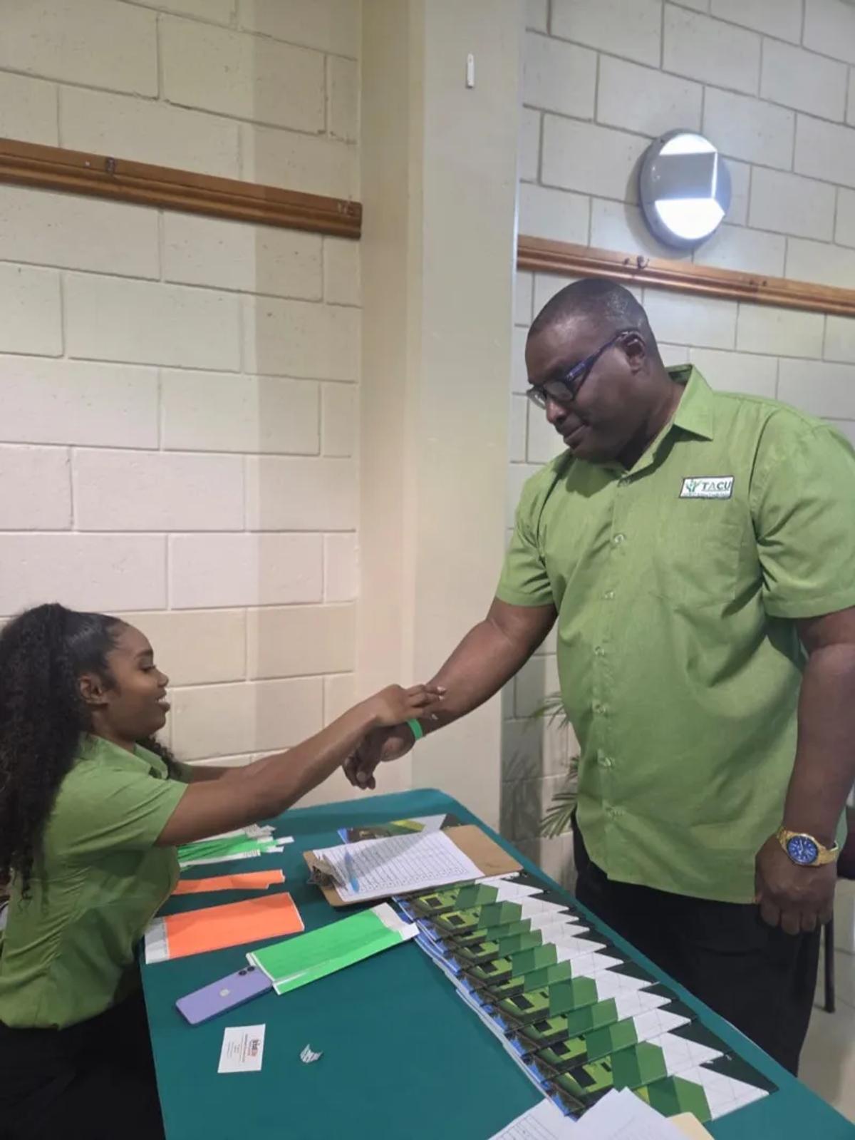 Two TACU staff members in green shirts at the registration table